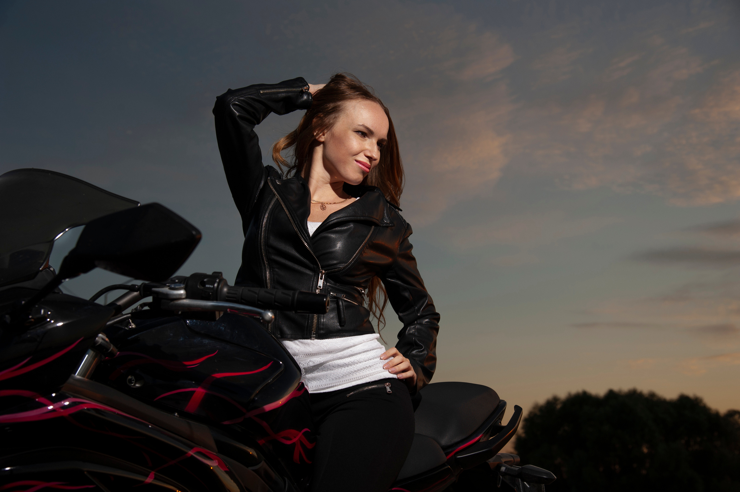 Девушка байкер на фоне закатного неба,сидящая на байке.