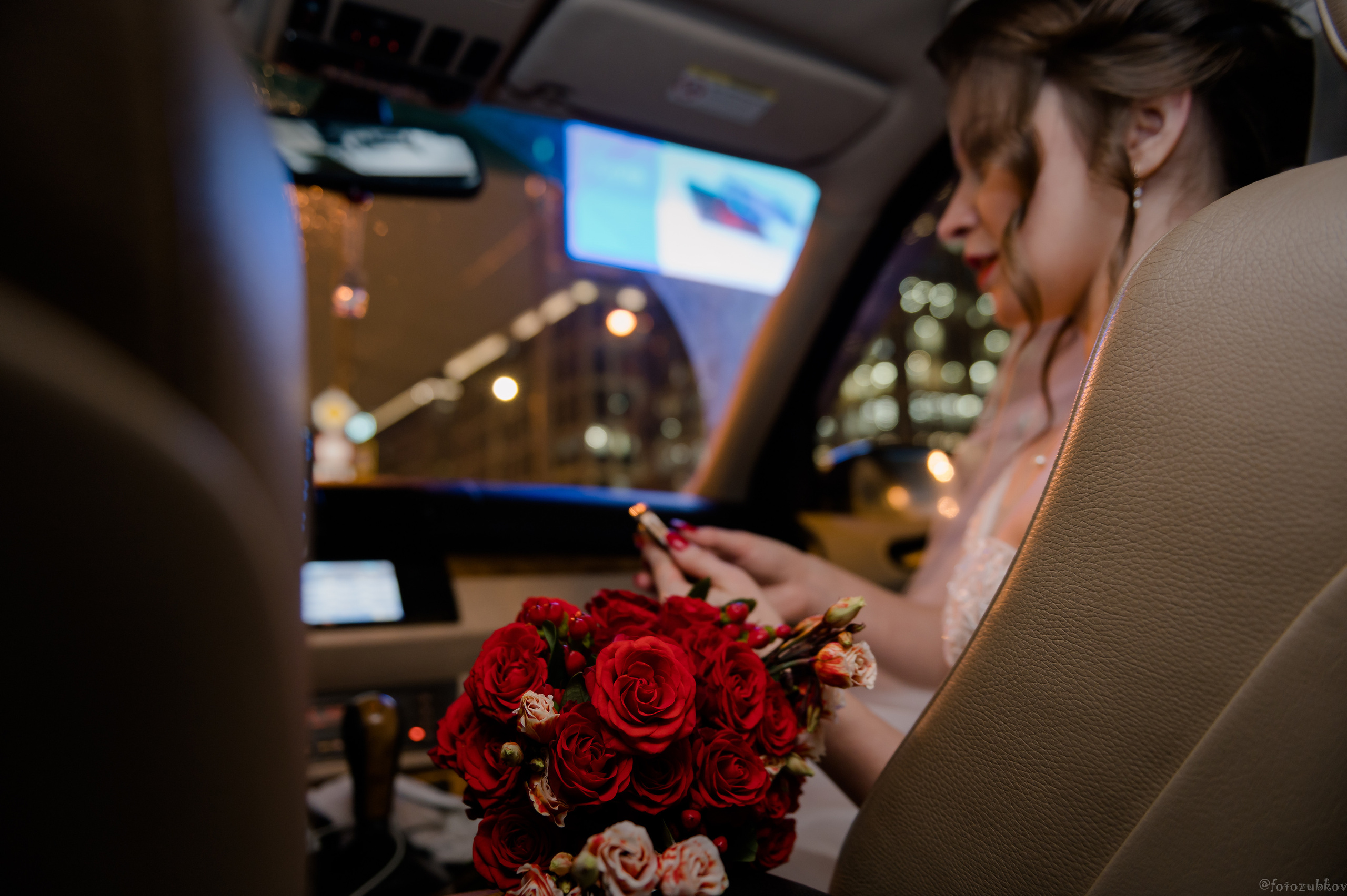 Счастливая невеста в машине с букетом цветов