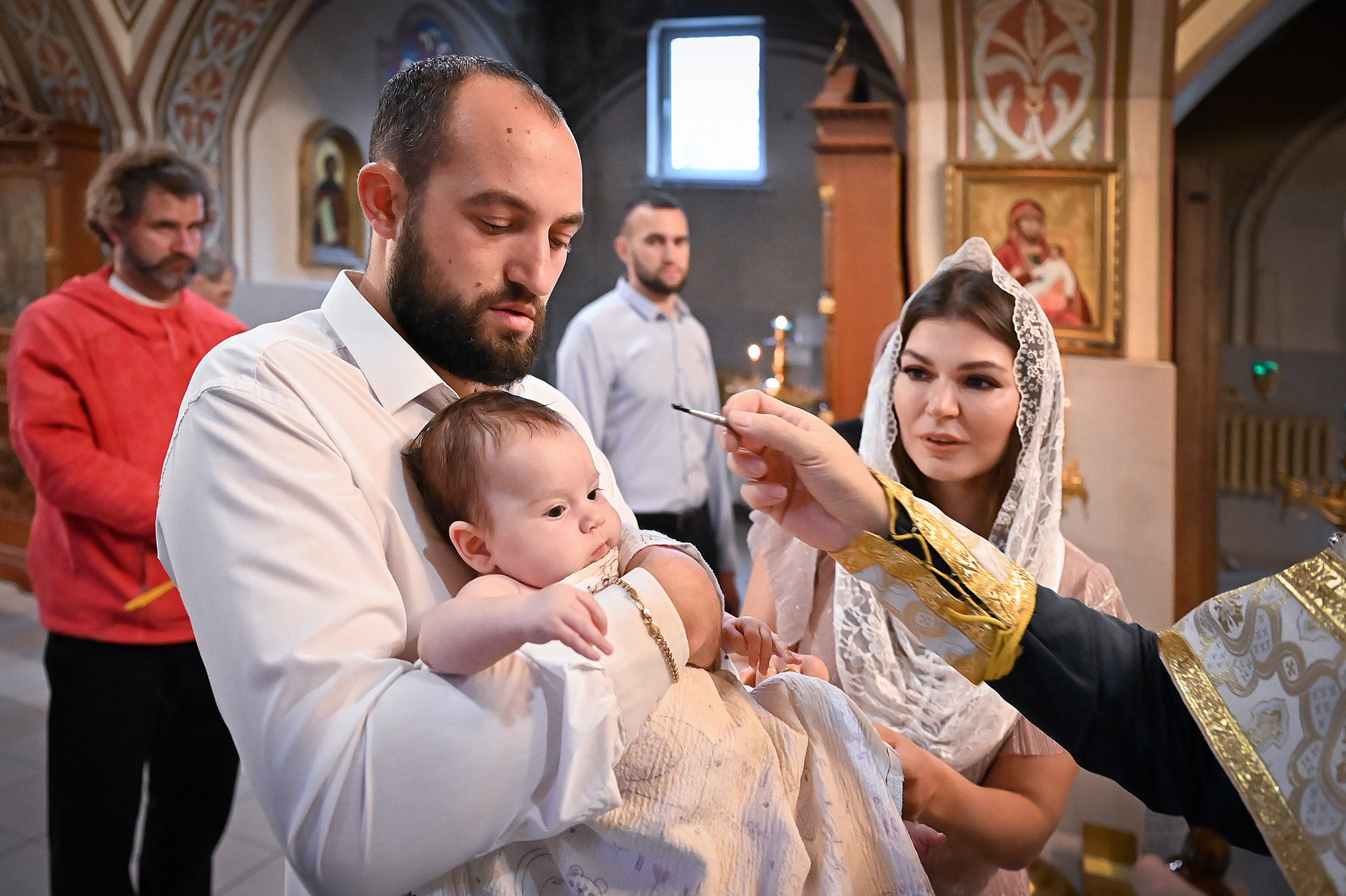 Девочка на руках у крестного в церкви