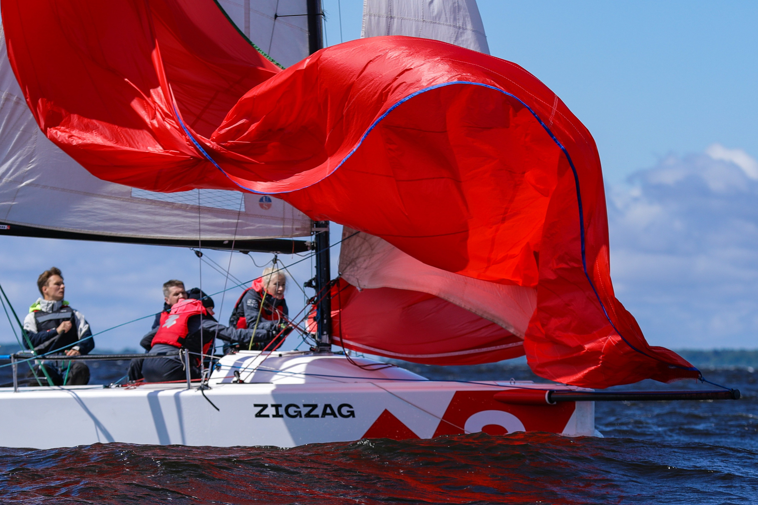Яхтсмены ставят красный генакер на регате.