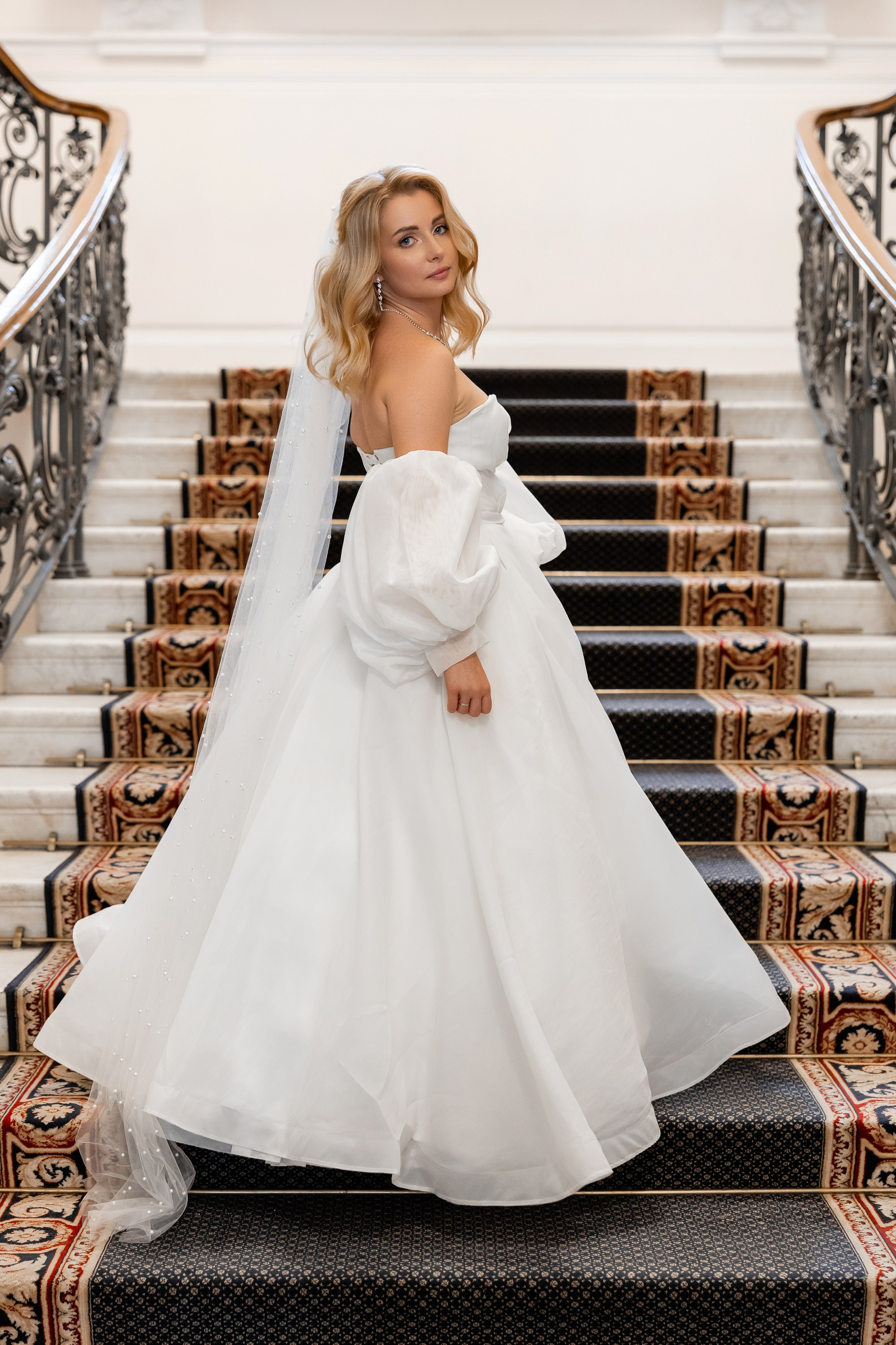 Невеста позирует перед фотографом на парадной лестнице дворца бракосочетания №2