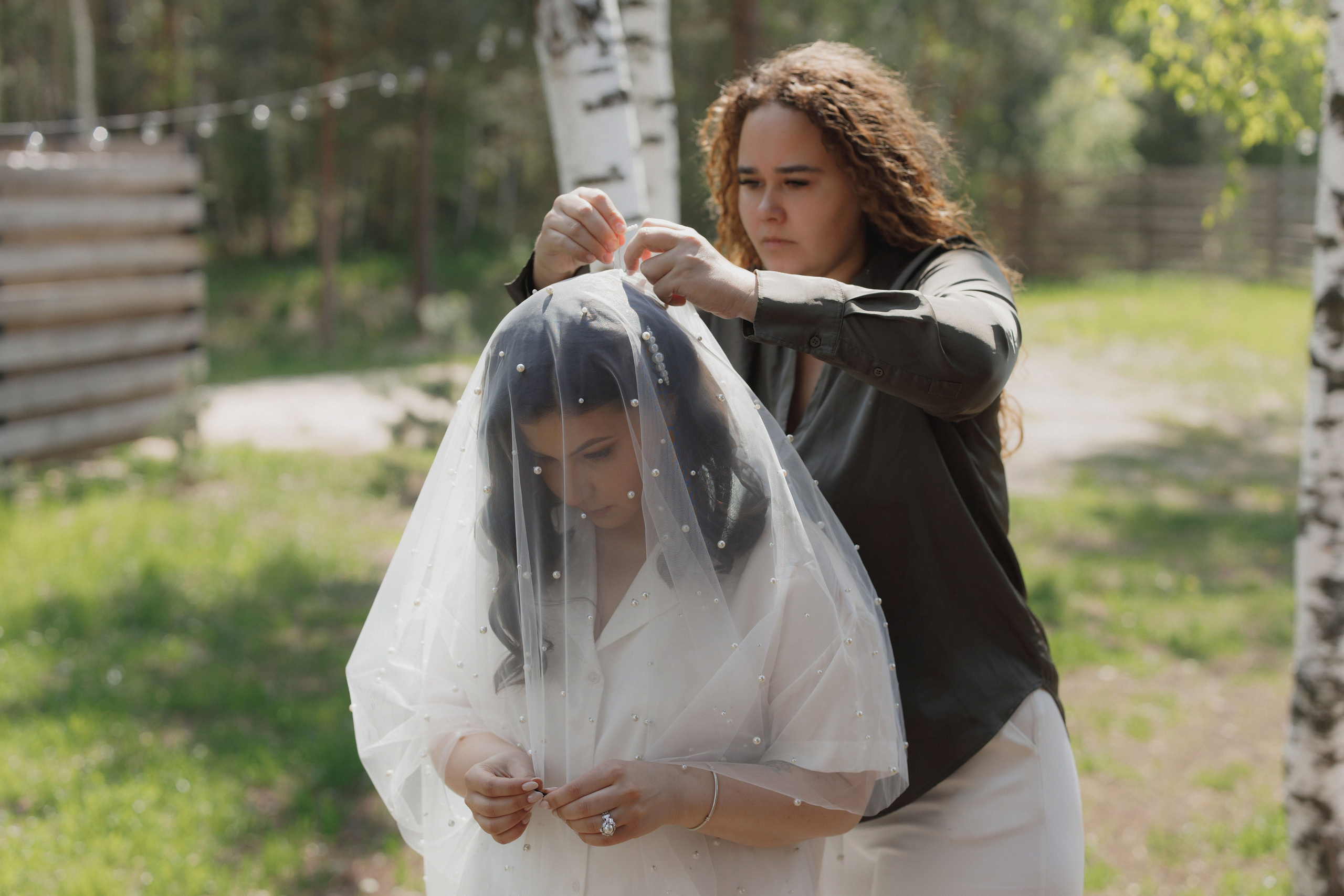 фотограф на свадьбу в рязани поправляет фату  невесте