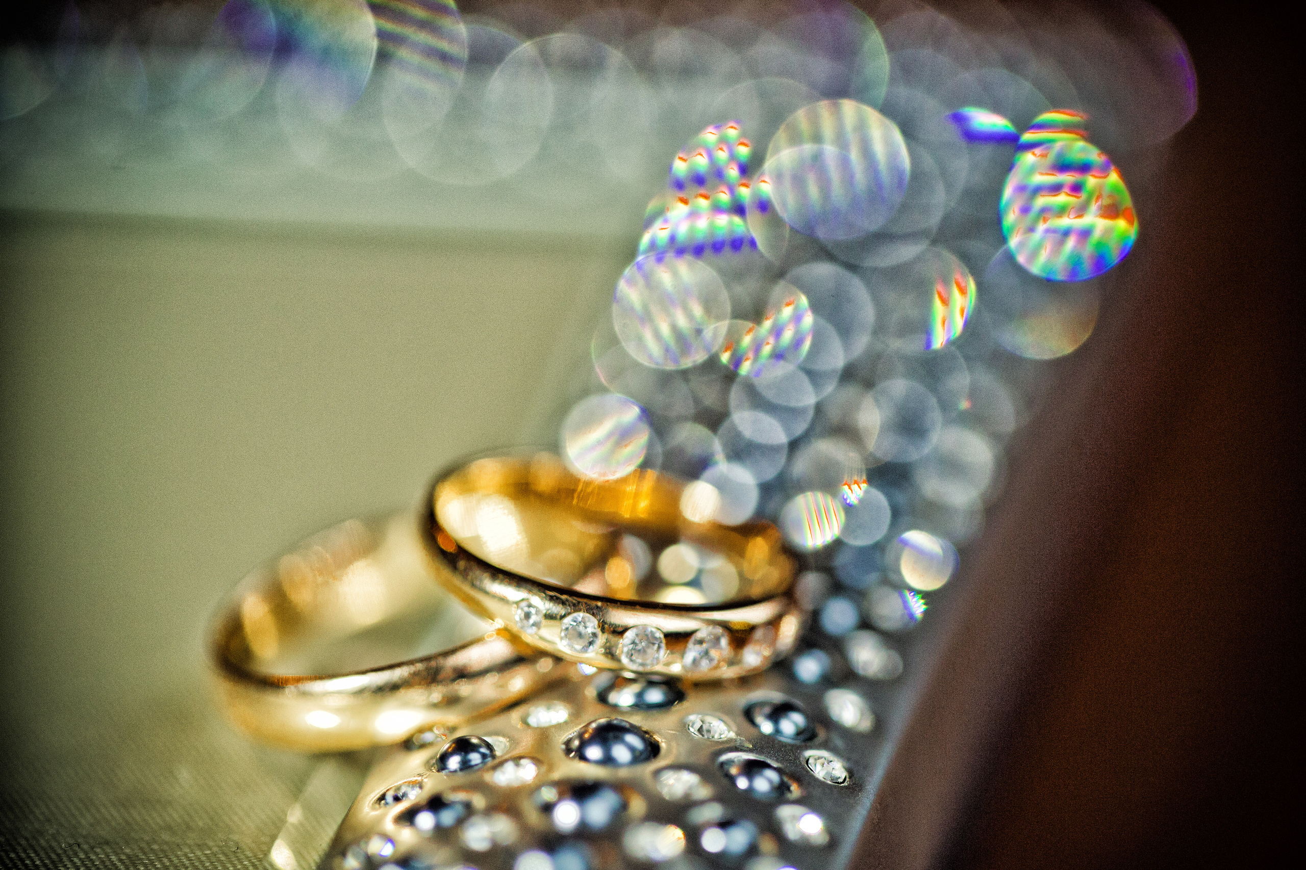 обручальные кольца с бриллиантами лежат на металлической поверхности с бликами