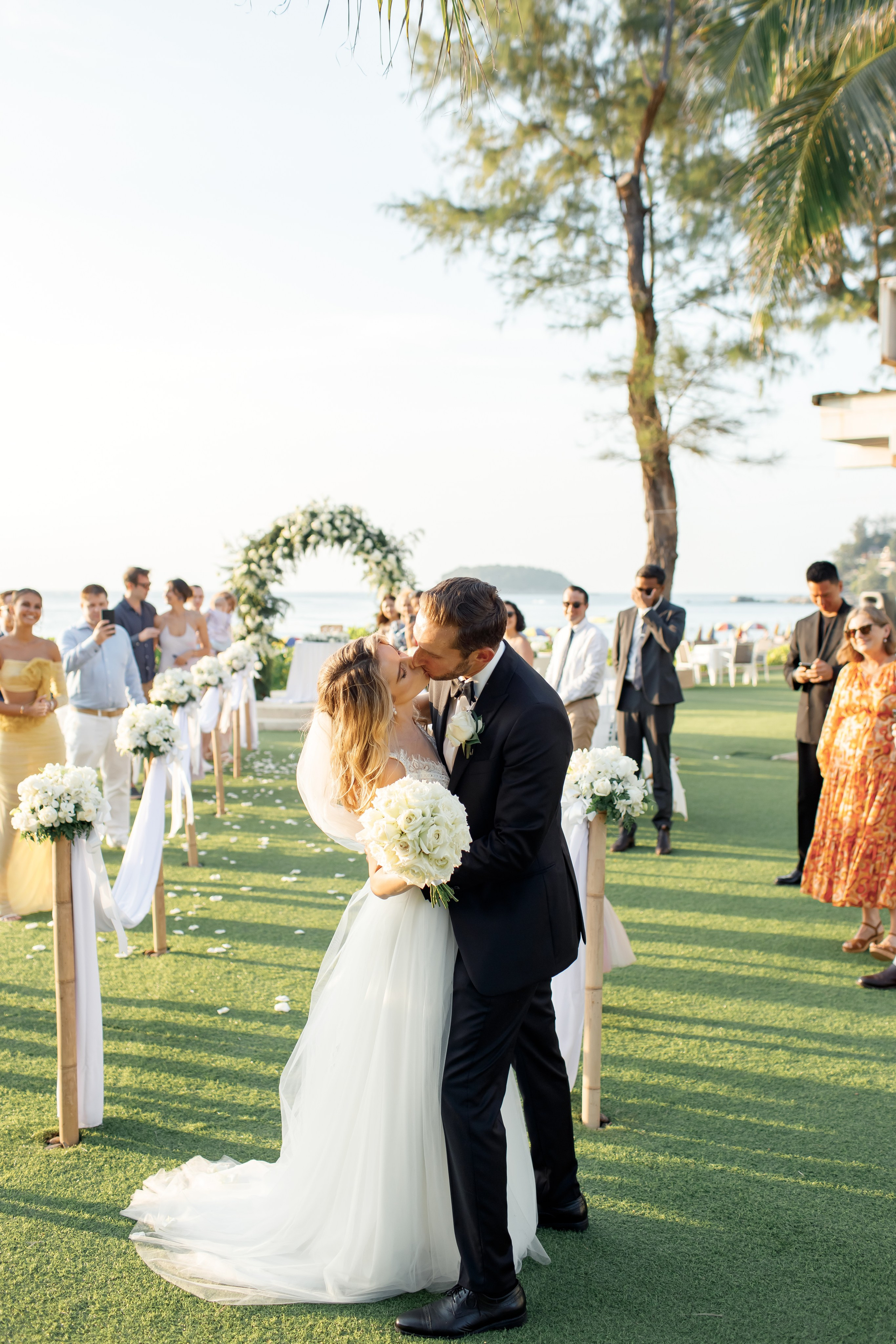 объятия и поцелуй после церемонии на фоне друзей