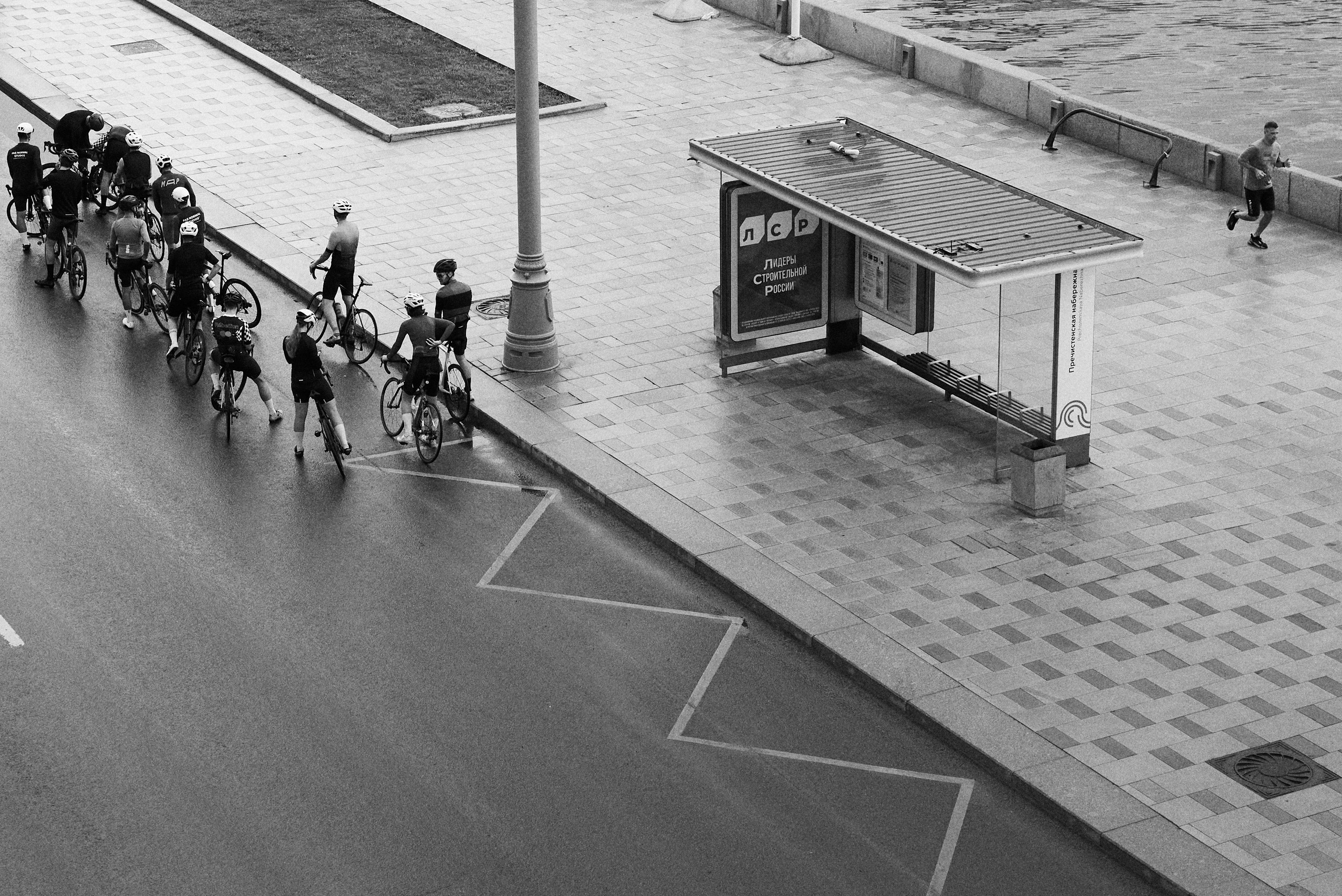 Велосипедисты на улице Москвы. Ремонт велосипеда прямо в пути. Пробегающий мимо спортсмен на утренней прогулке.