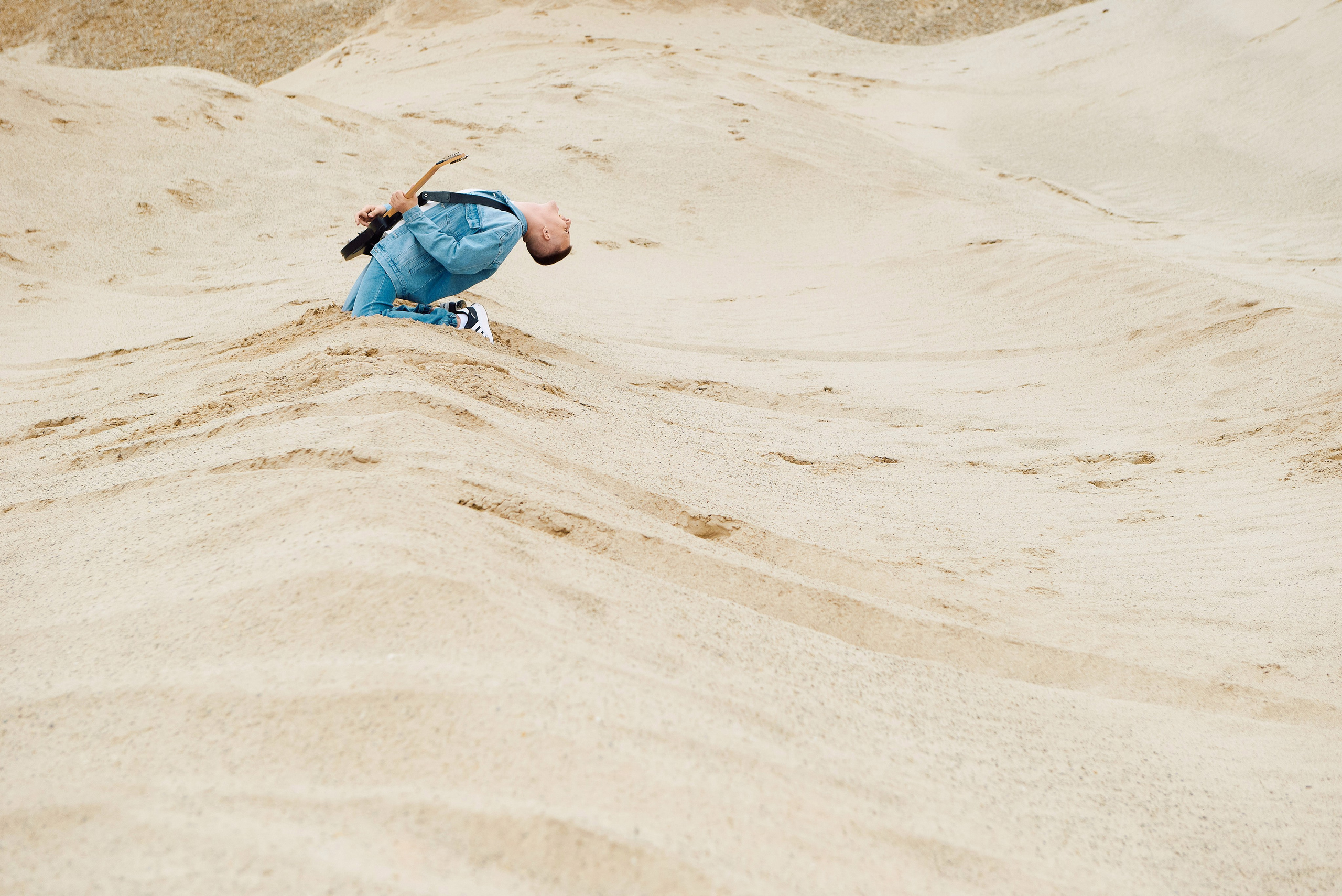 Парень играет на гитаре в пустыне