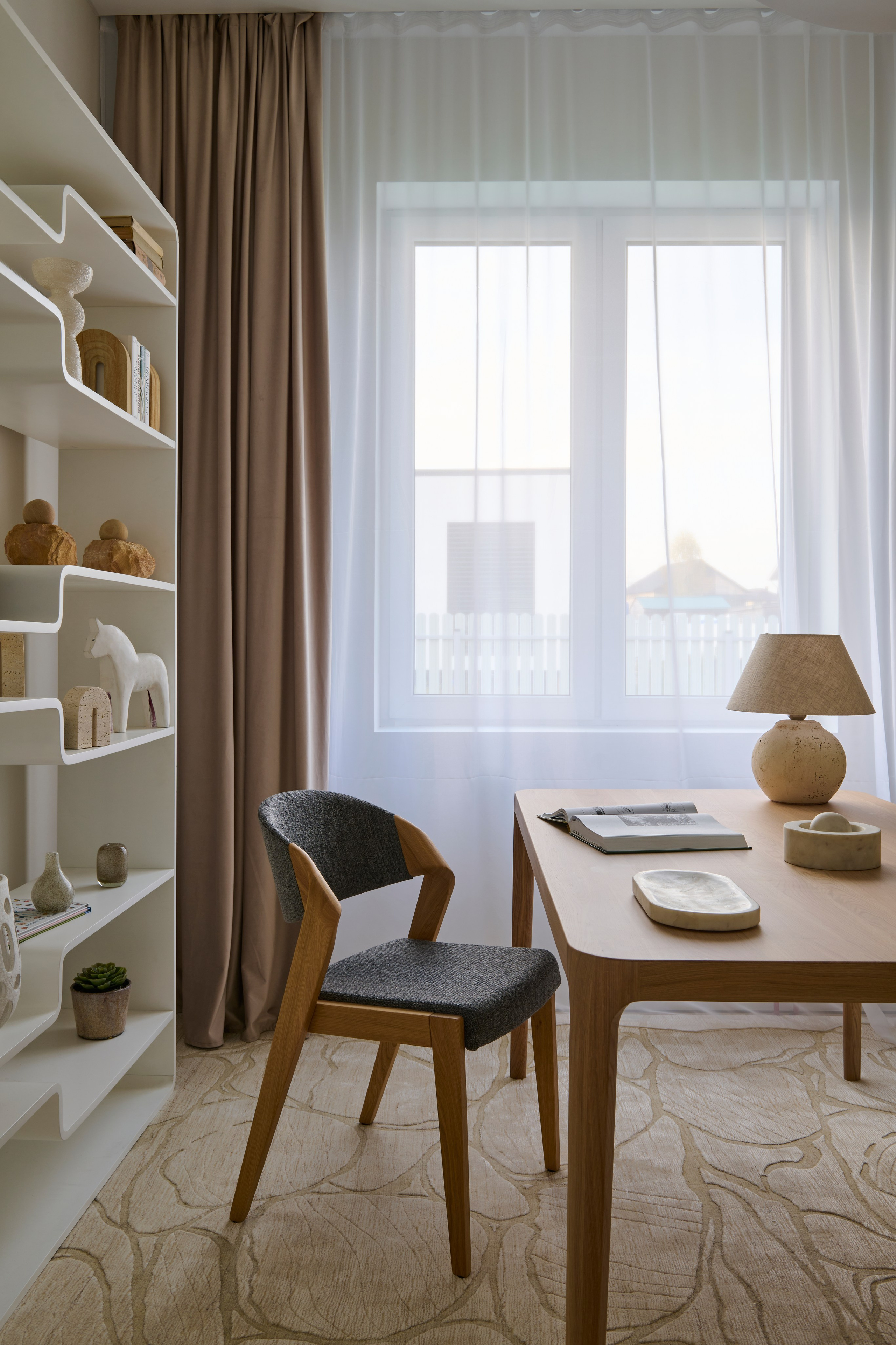 Небольшая зона у окна: стол, стул и стеллаж с декором