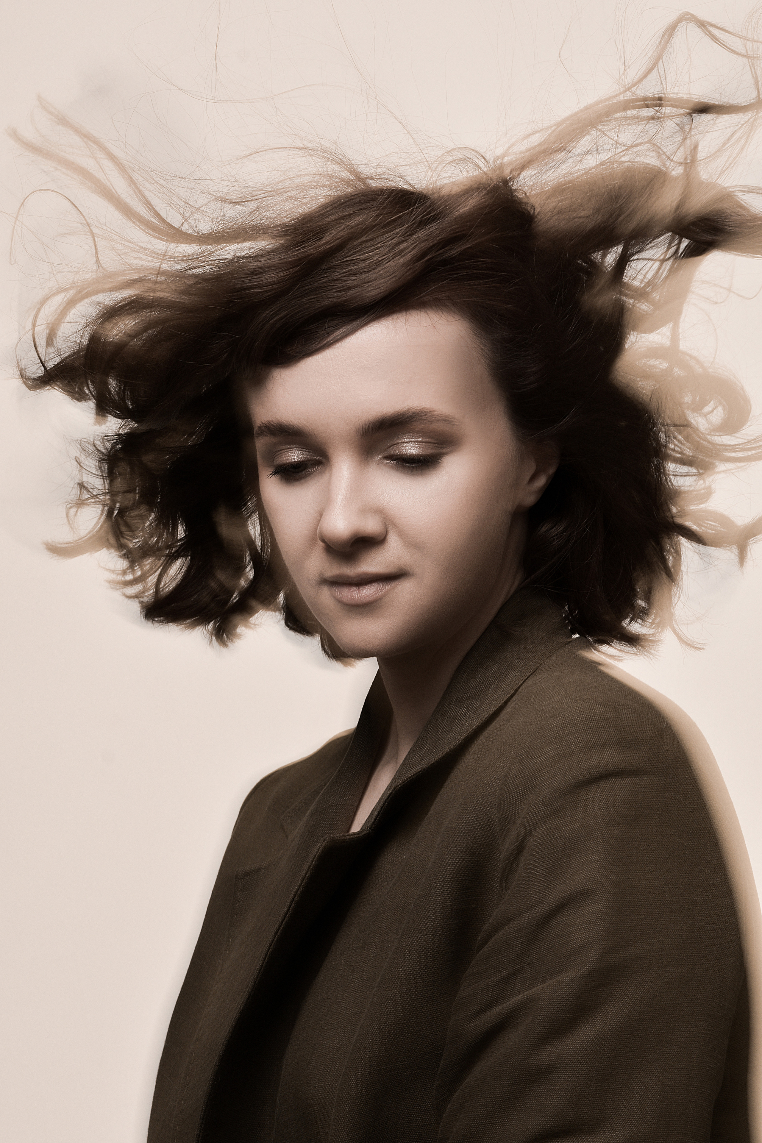 Девушка с каре, в пиджаке цвета хаки, портрет в студии, волосы раздувает ветер