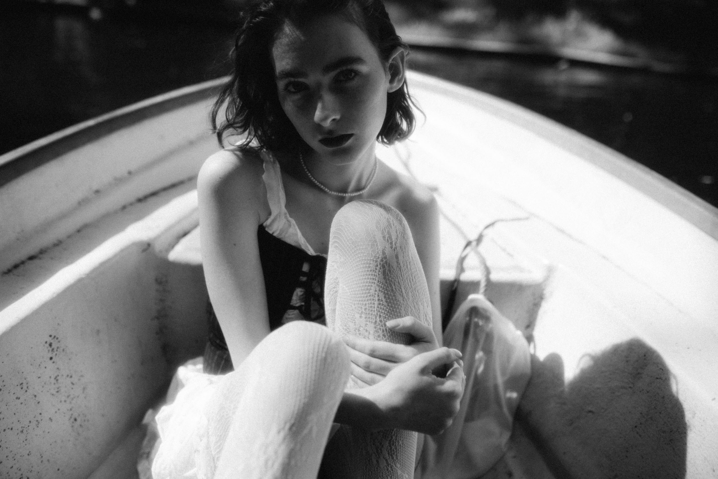 Девушка сидит на дне лодки в солнечный день