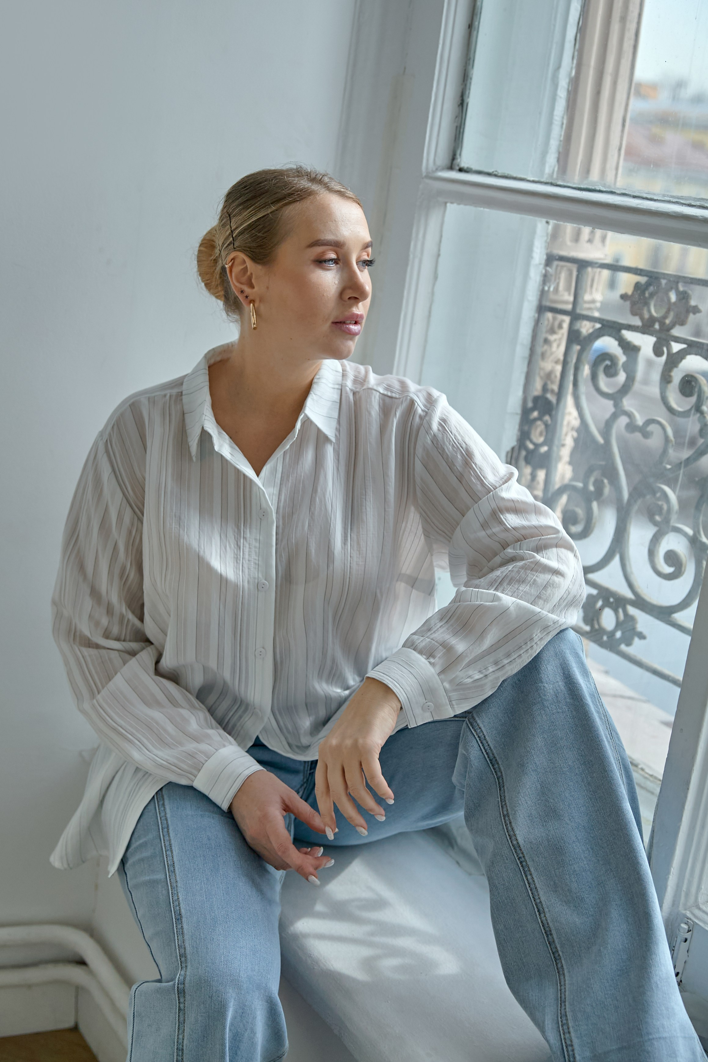 Девушка сидит на окне в белой рубашке Varra