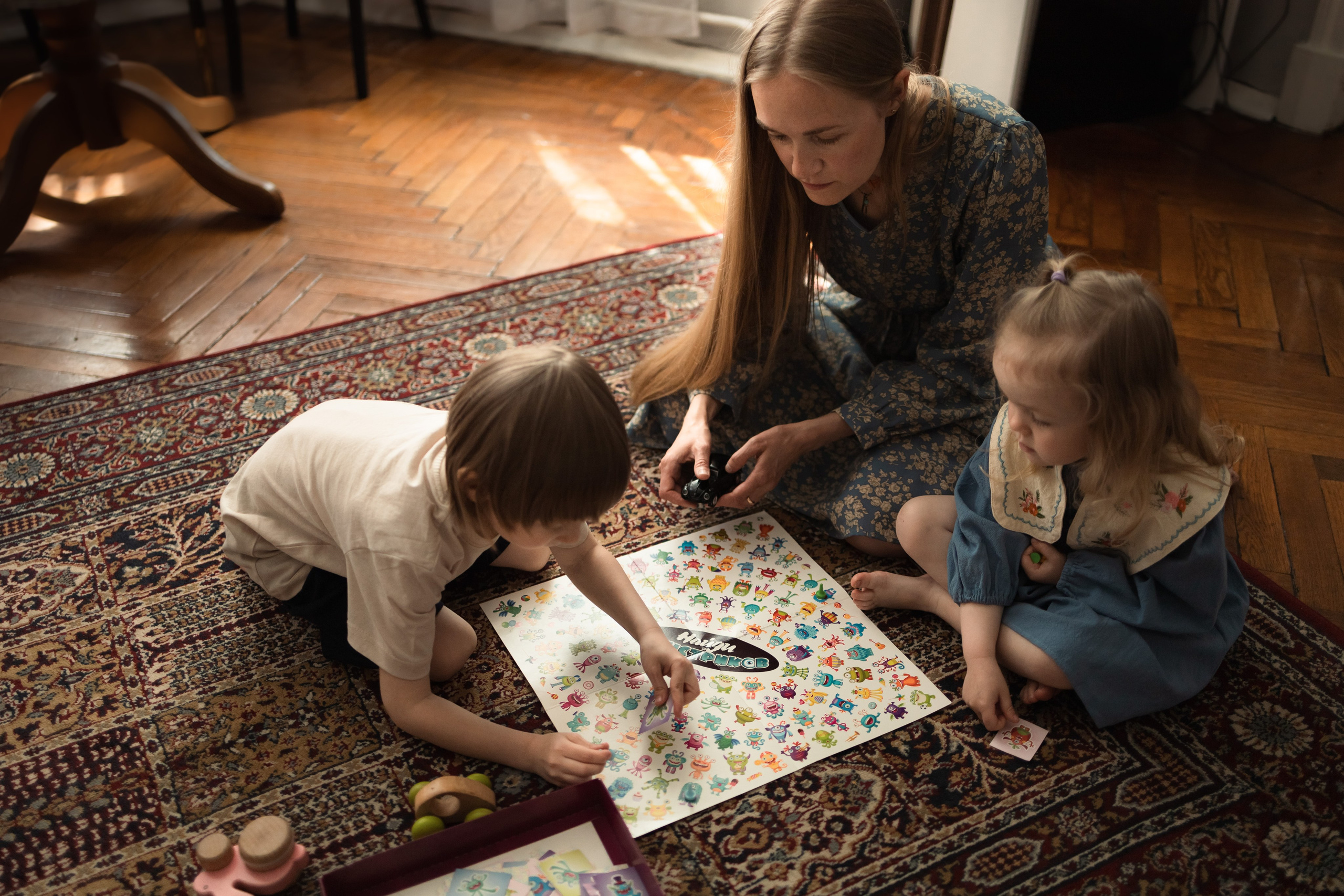 Семейные развлечения: мама, сын и дочь играют в настольную игру в комфортной домашней атмосфере с мягким светом из окна