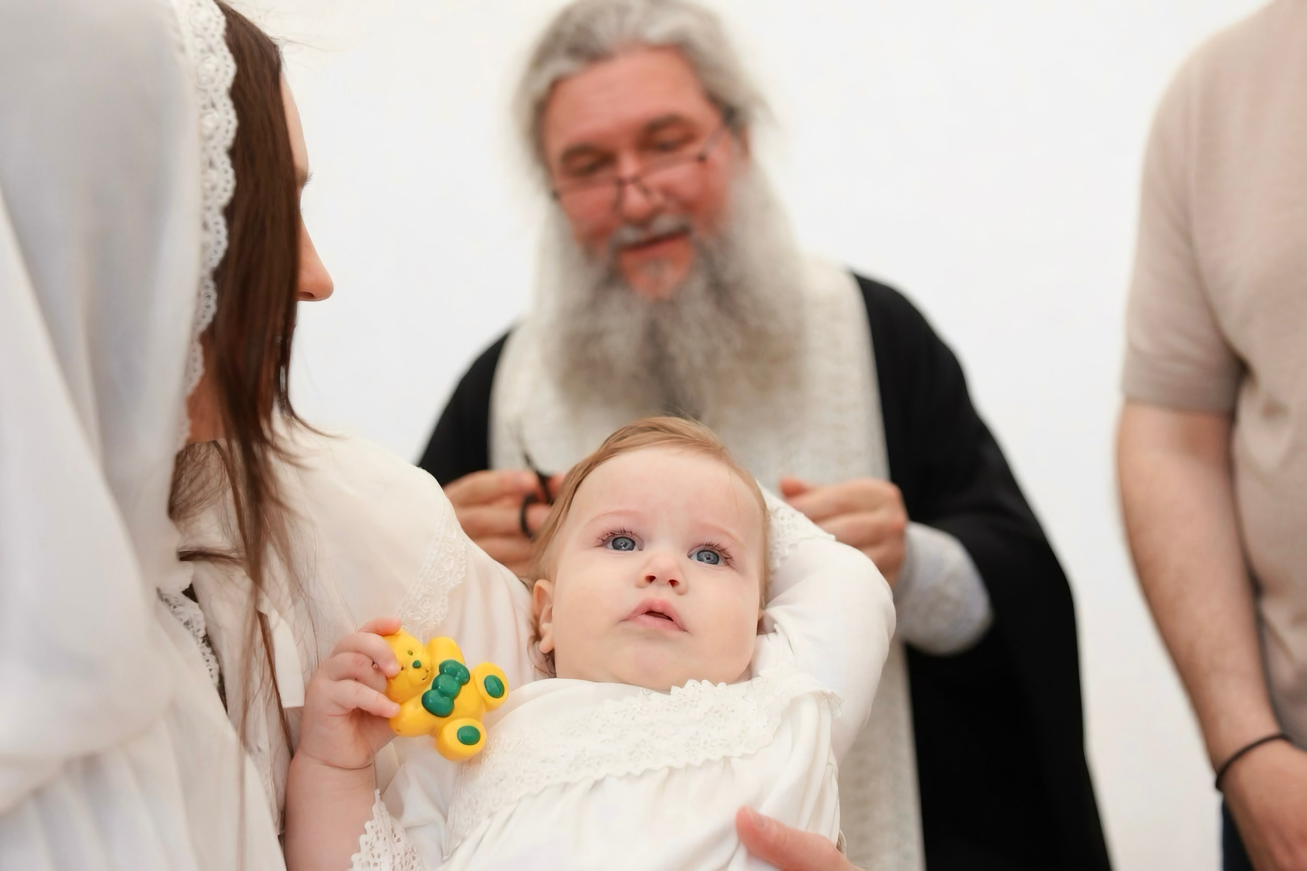 Постриг — священник срезает прядь волос младенца, крестная рядом, светлый фон — Екатеринбург, Илья Антропов