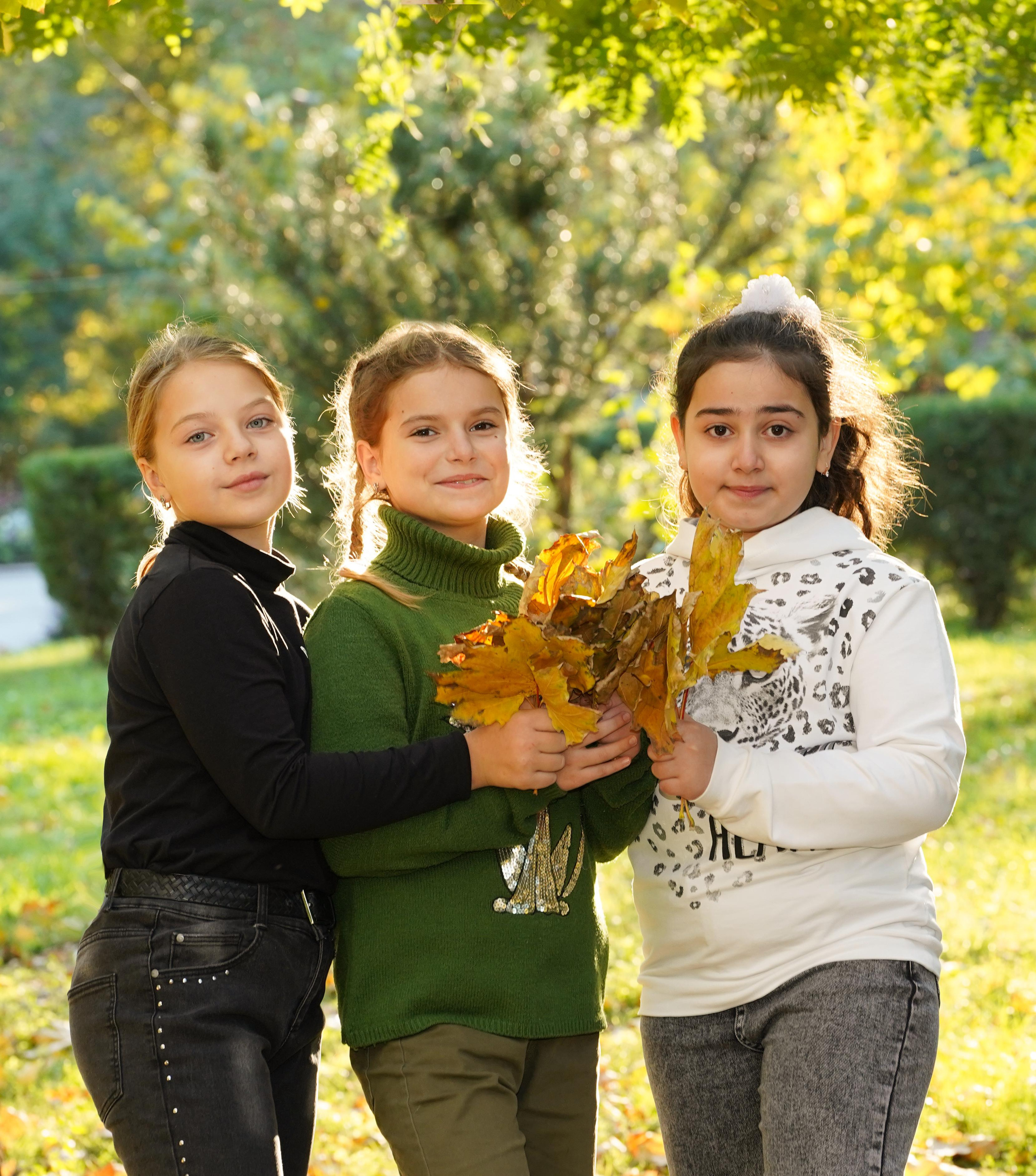 школьницы в парке с букетом из листьев