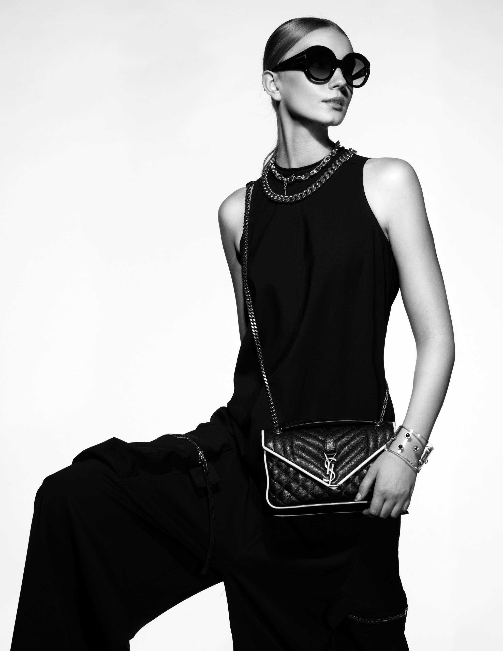 Fashion-портрет в студии: модель в total black образе с сумкой YSL и крупными аксессуарами.