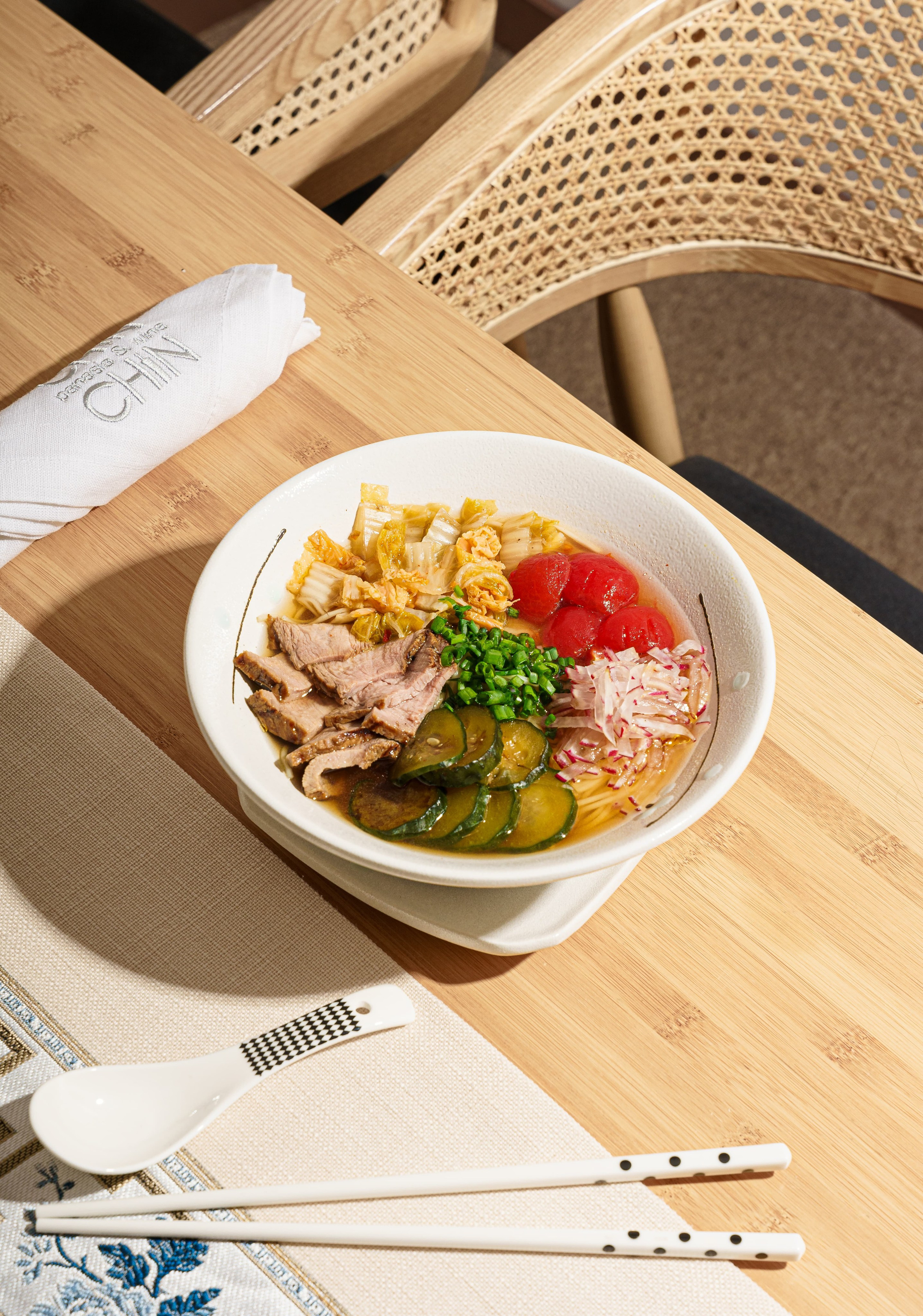 Japanese ramen with egg, green onions, and sesame seeds in broth, served in a ceramic bowl. Top view food photography