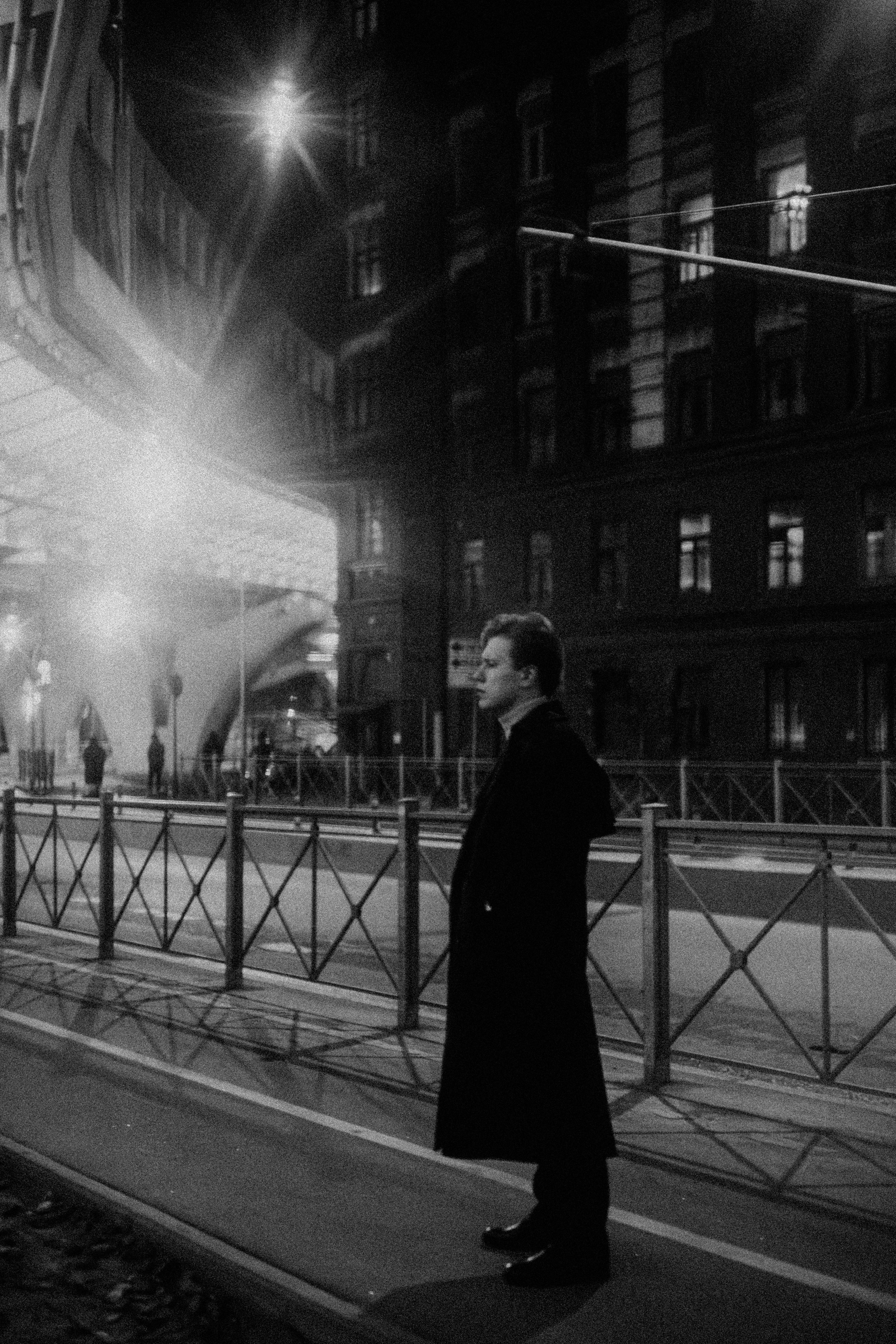 Молодой человек ночью задумался под мостом