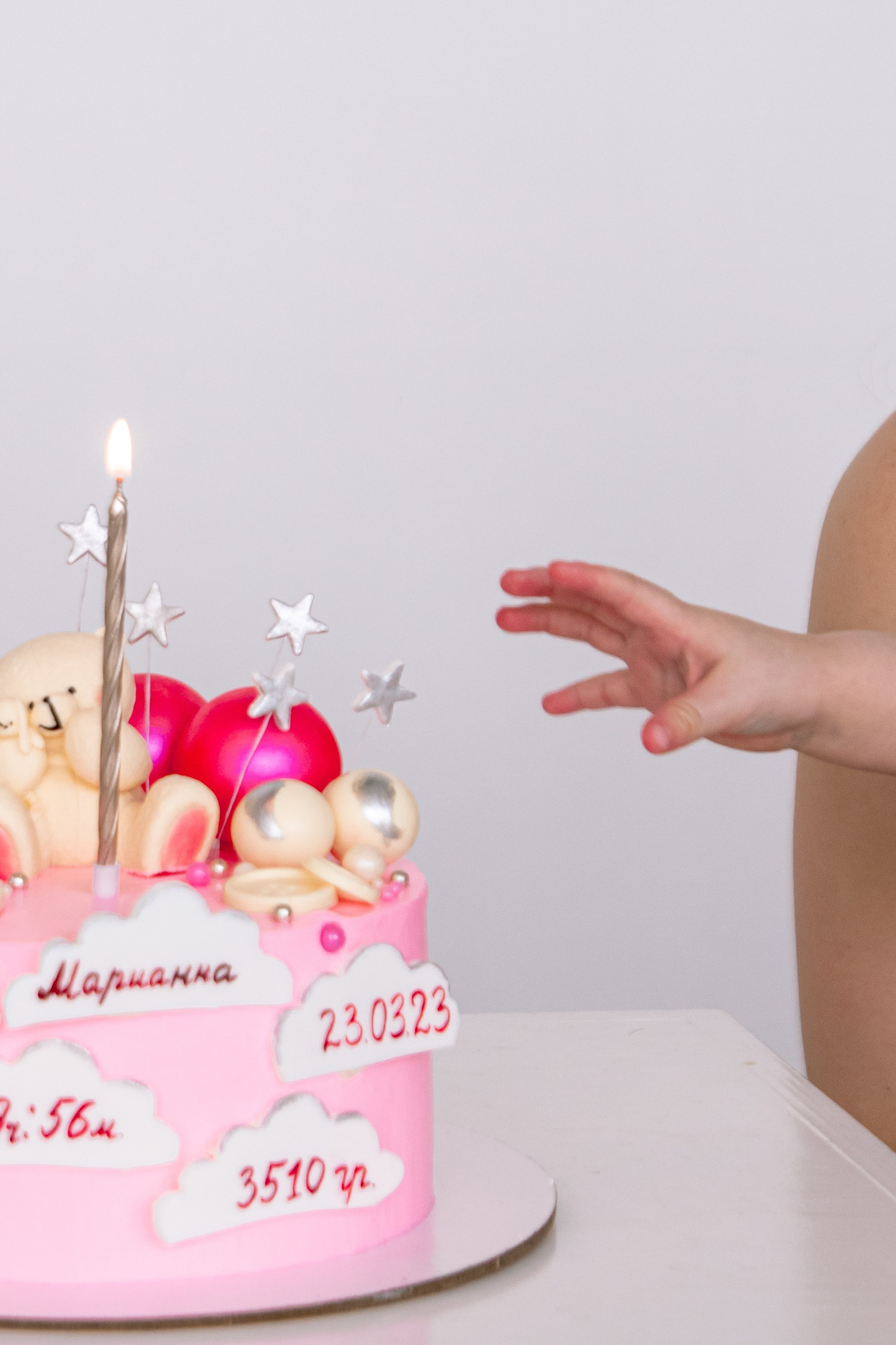 детская рука тянется к тортику со свечкой в честь первого дня рождения