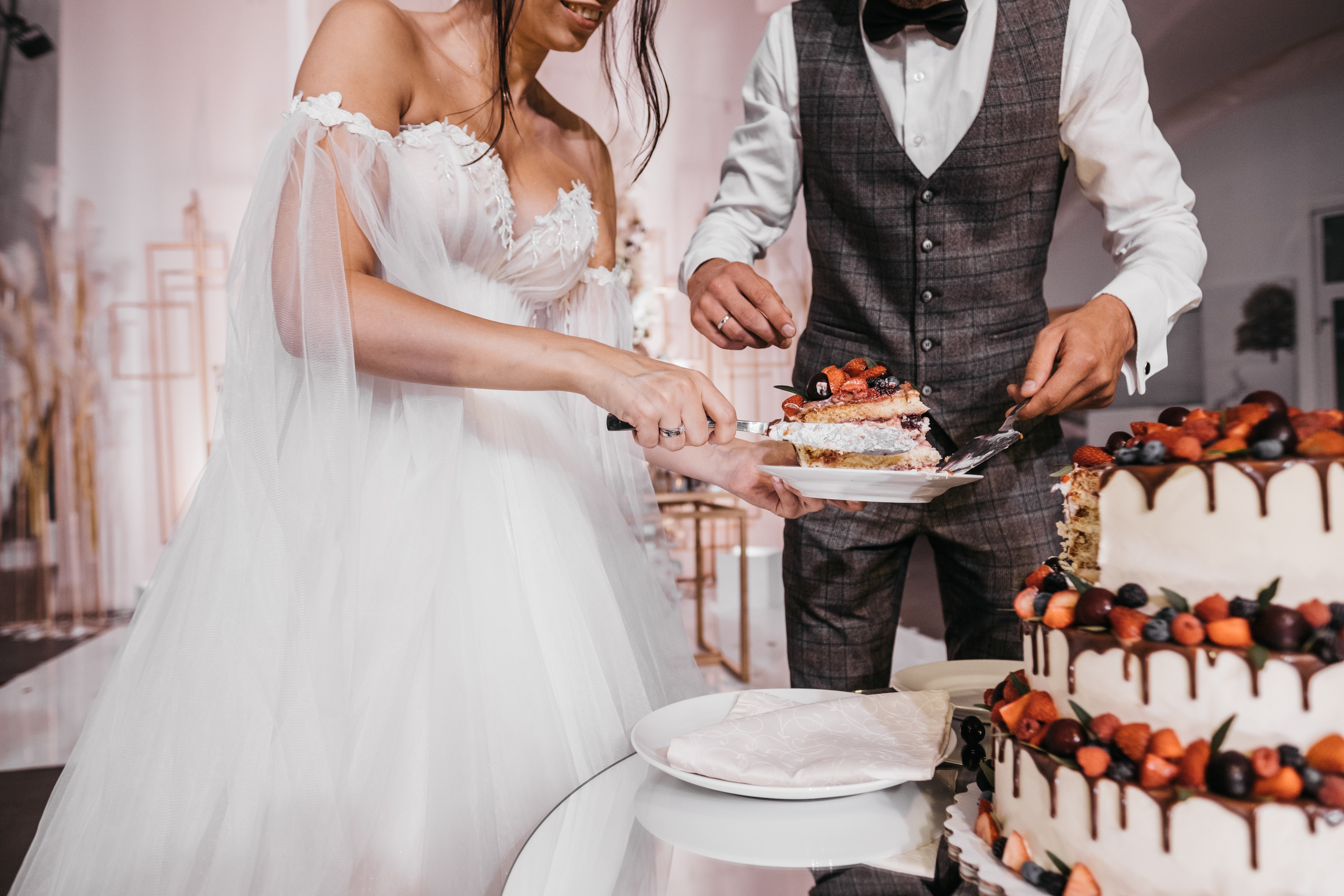 Молодожены вместе разрезают свадебный фруктовый торт.