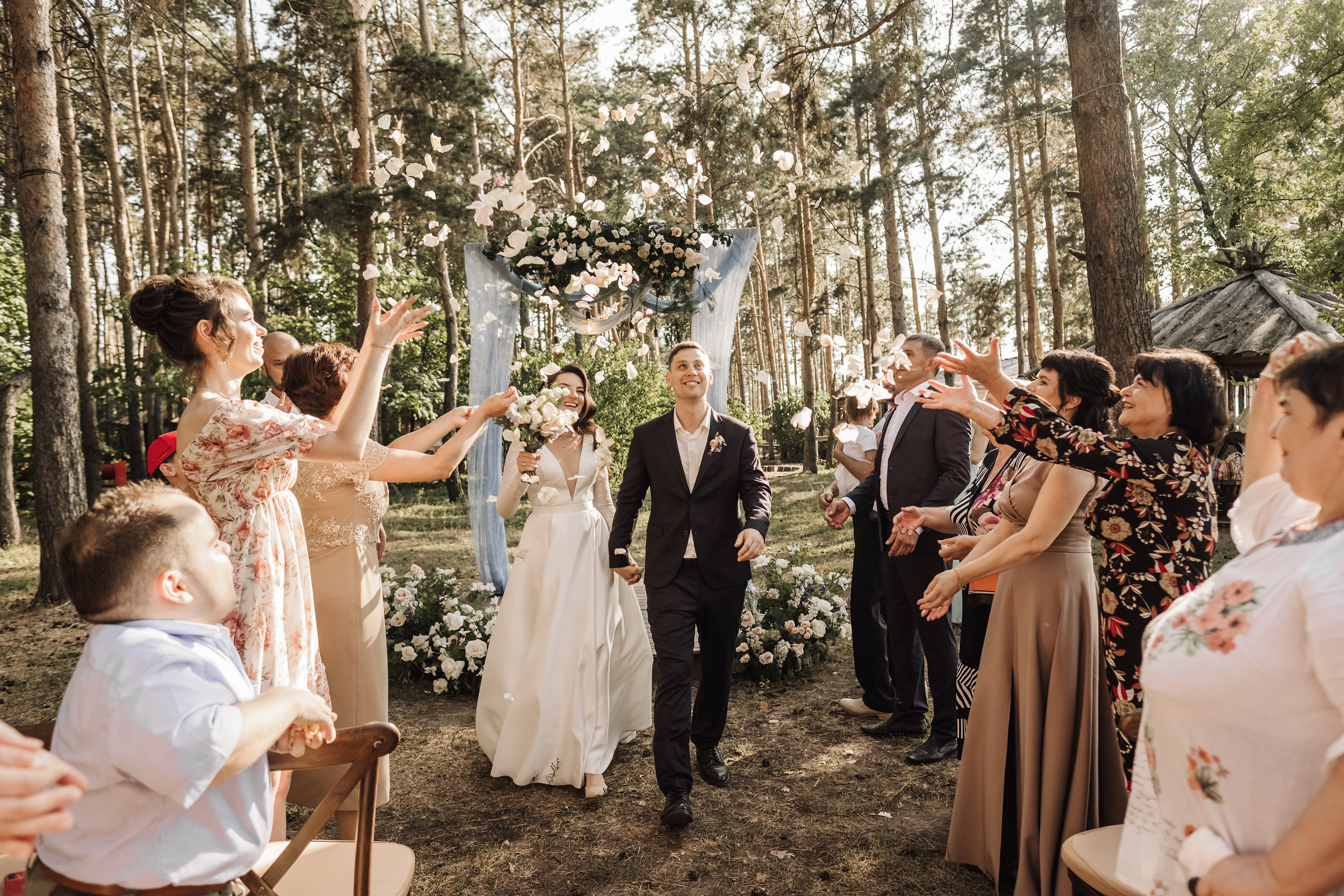 Гости встречают молодоженов подкидывая над ними лепестки роз.