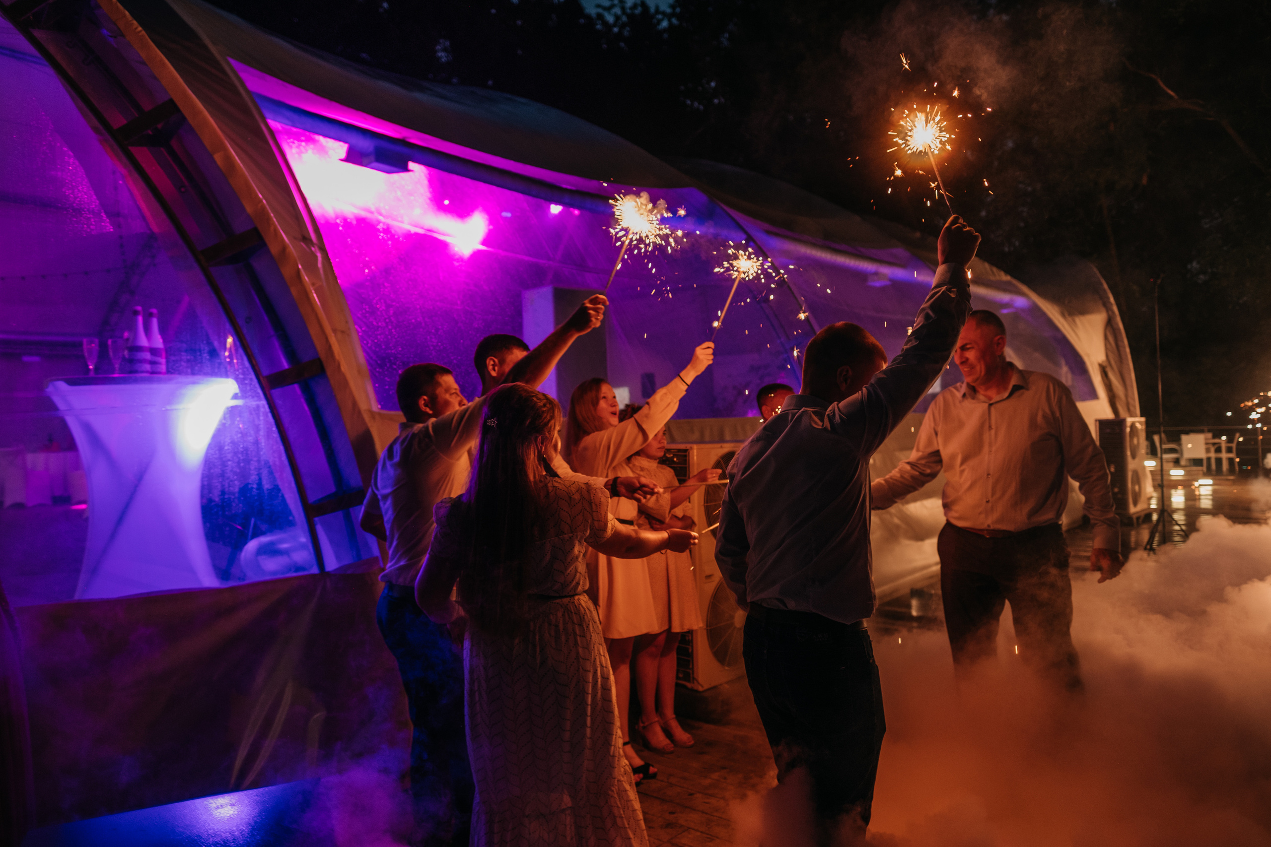 Гости держат бенгальские огни делая коридор для молодожен.