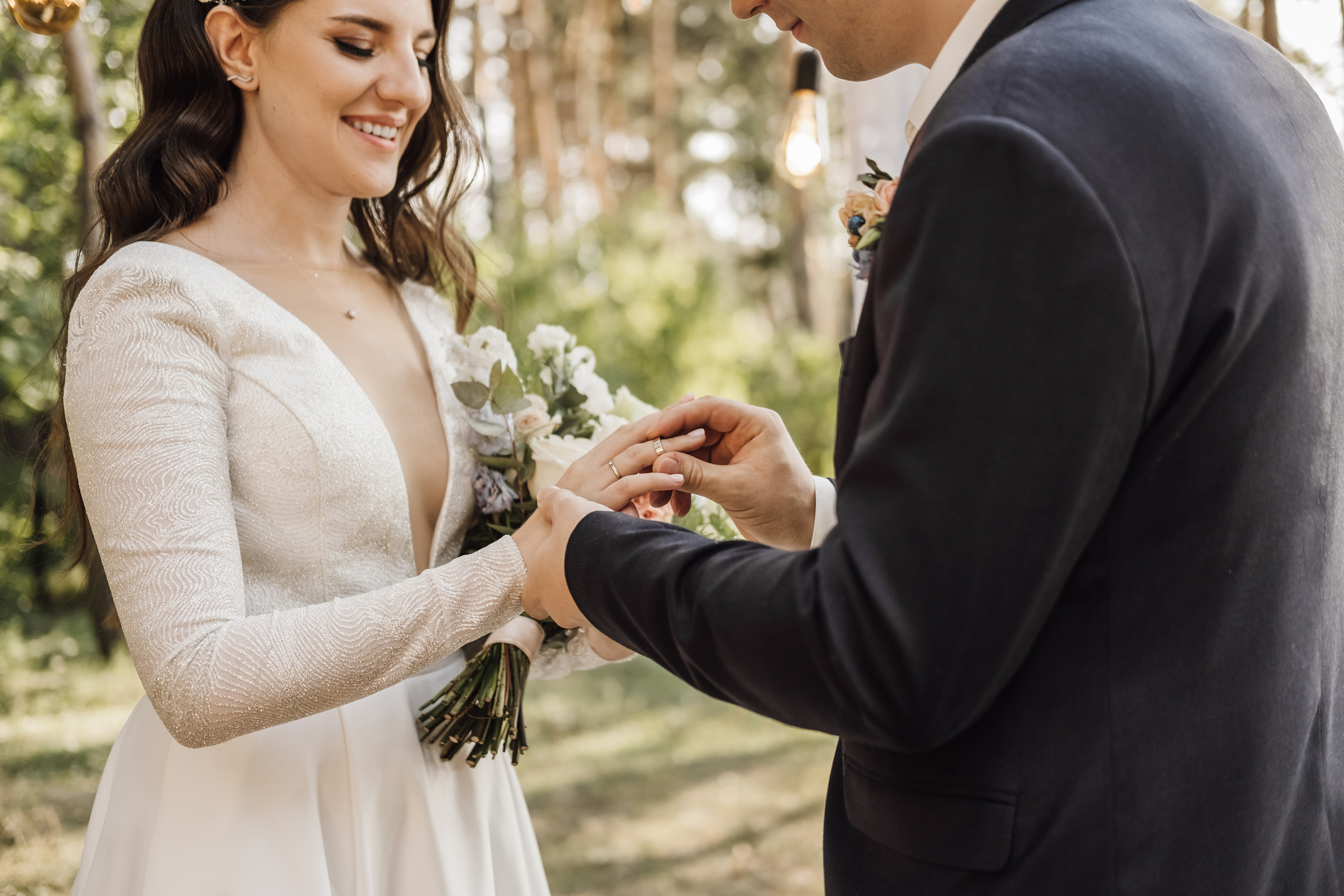 Жених одевает невесте кольцо на безымянный палец.