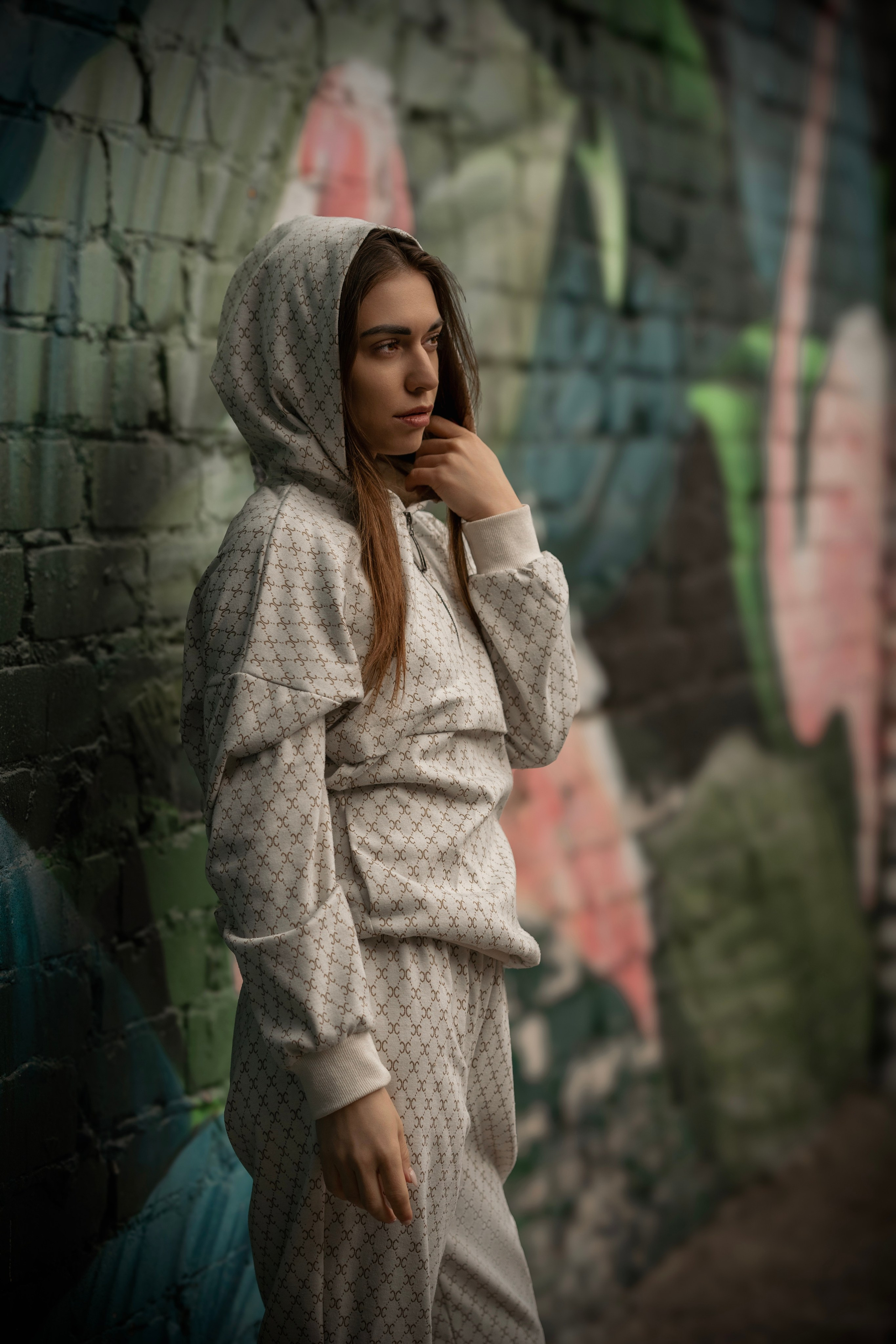 Девушка в спортивном костюме, стоящая у стены с граффити