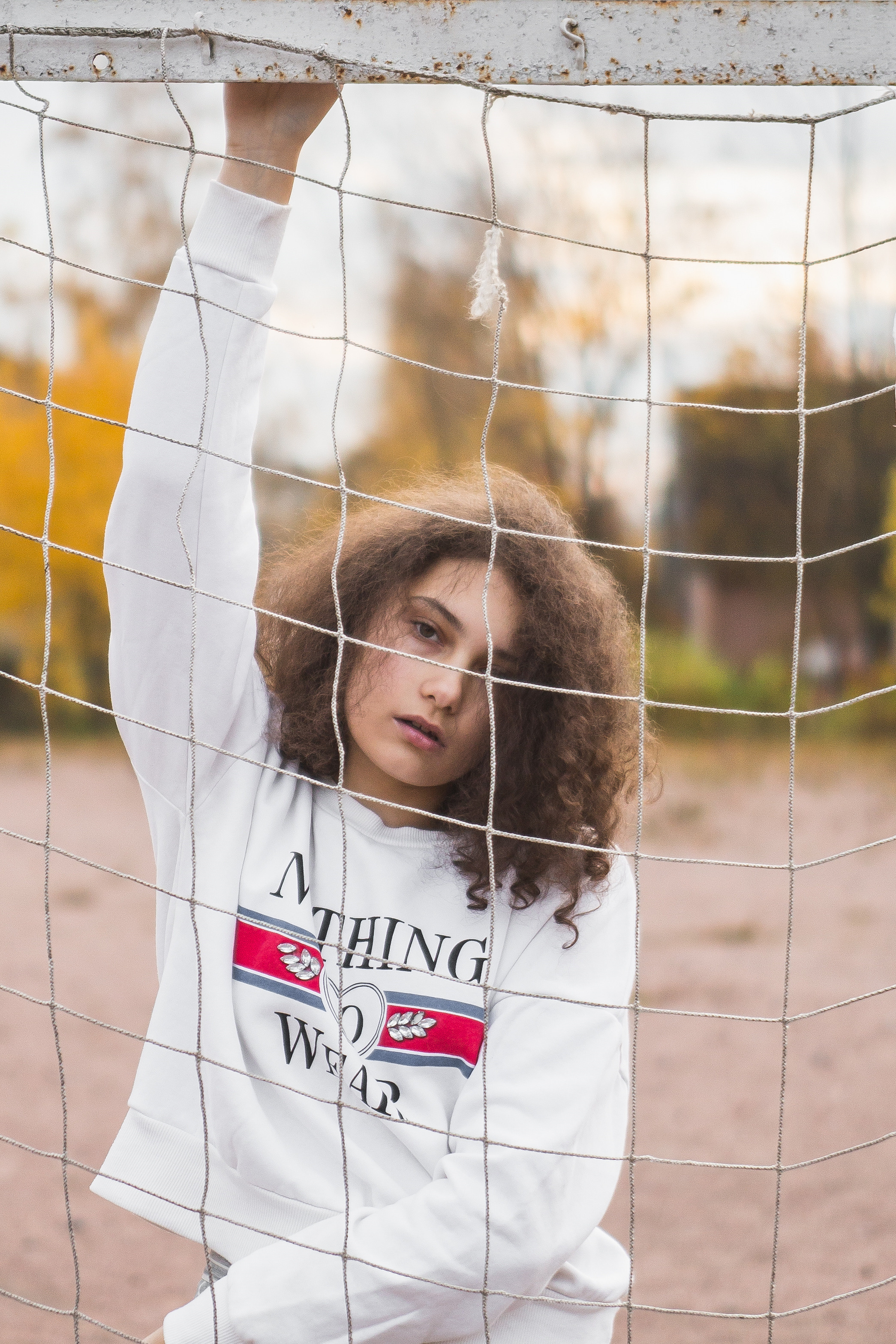 Кудрявая девушка на спортивной площадке золотой осенью