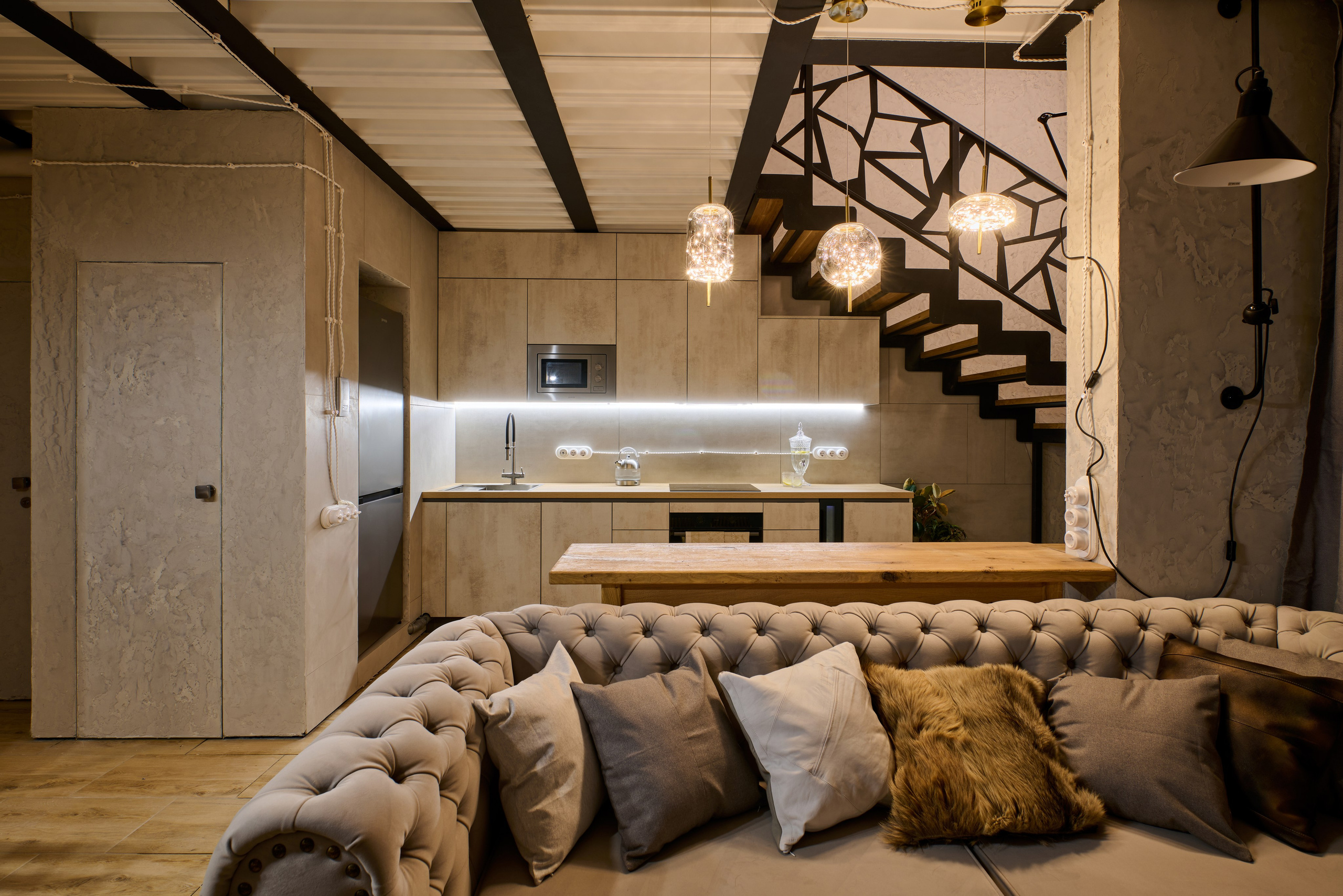 Гостиная: большой диван, лестница, кухня на фоне, тёплая палитра