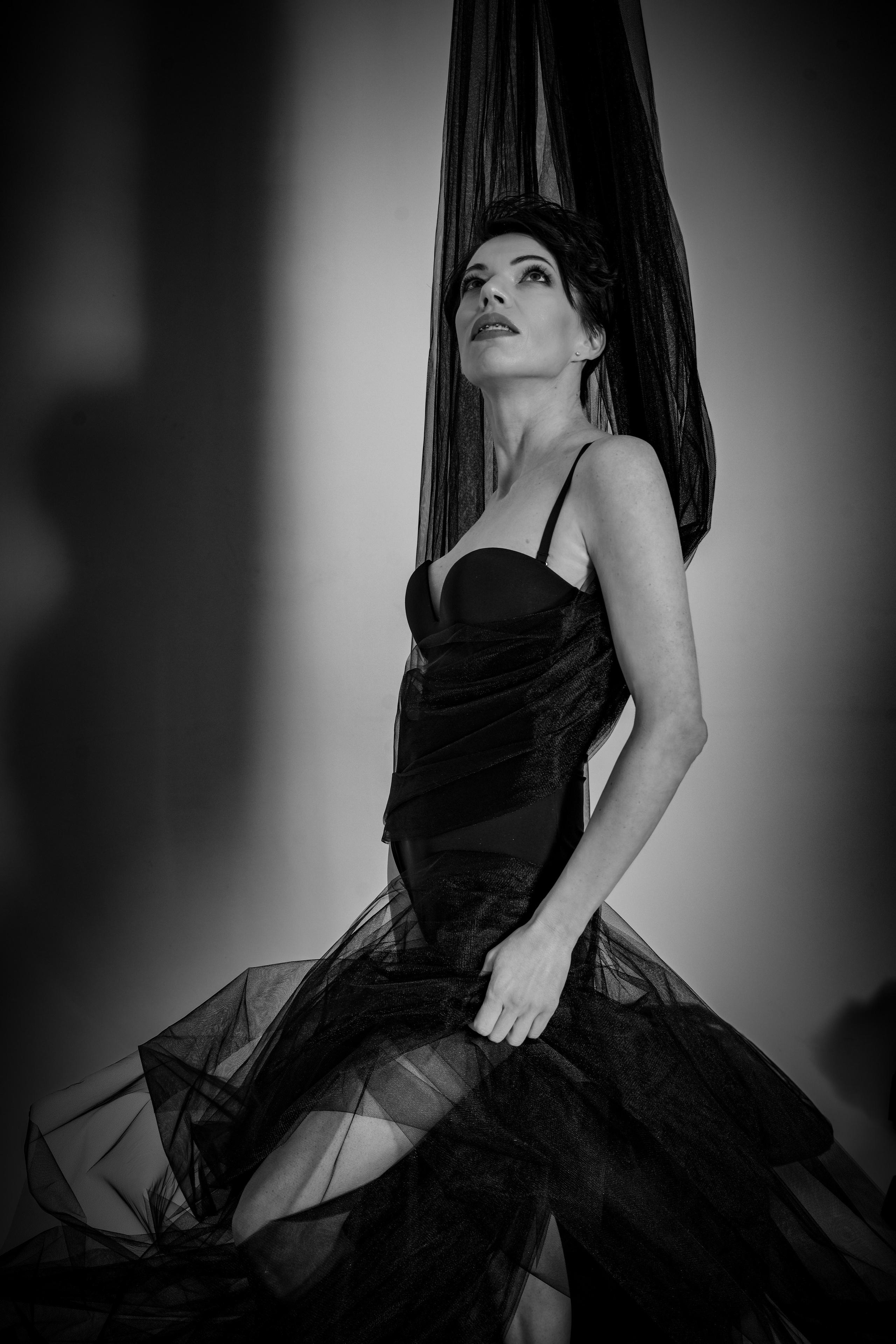 Молодая девушка в нижнем белье стоит в фотостудии держа фатин руками