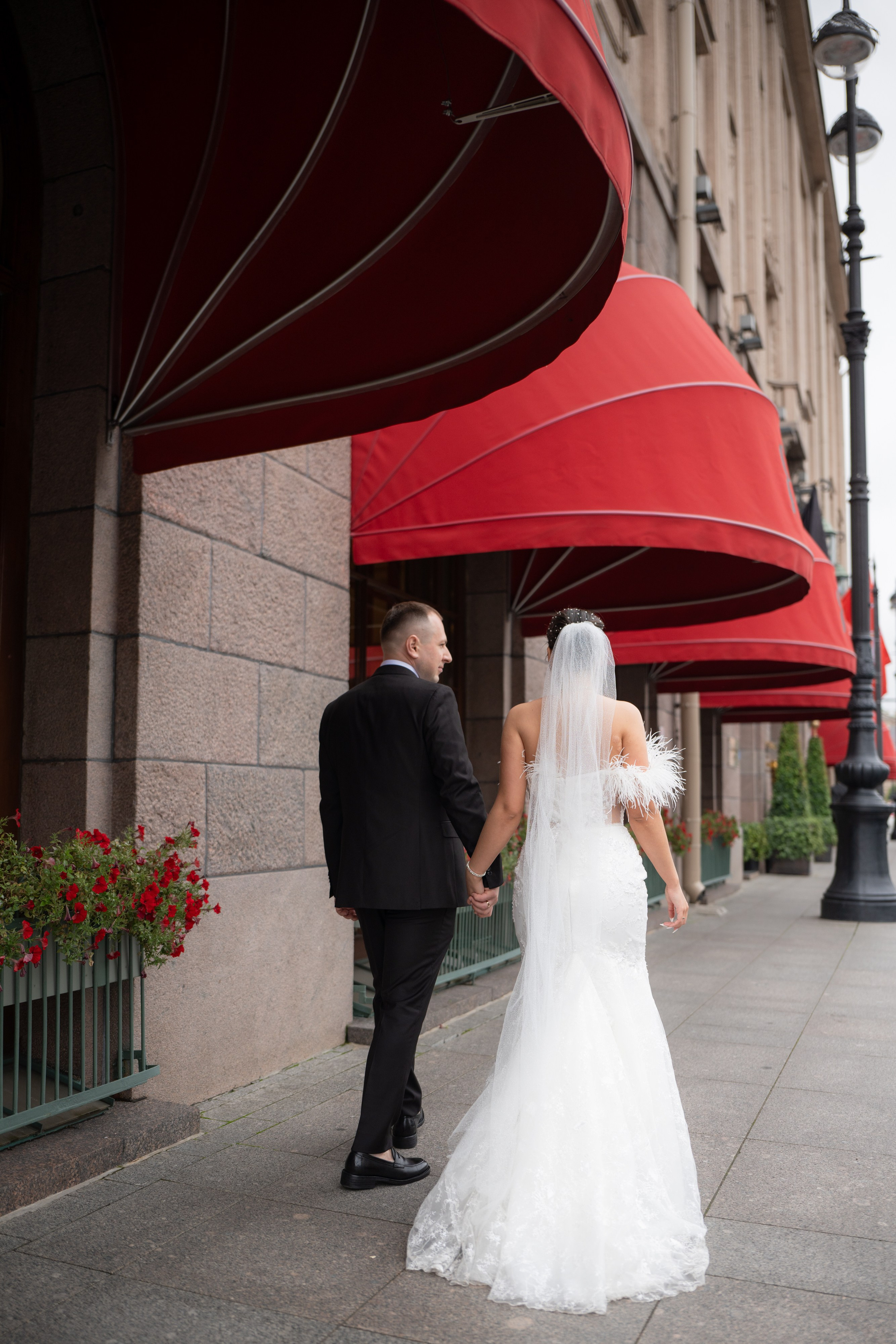 жених и невеста целуются под красными зонтами гостиницы Астория. Свадебная фотосессия у Астории в Санкт-Петербурге.