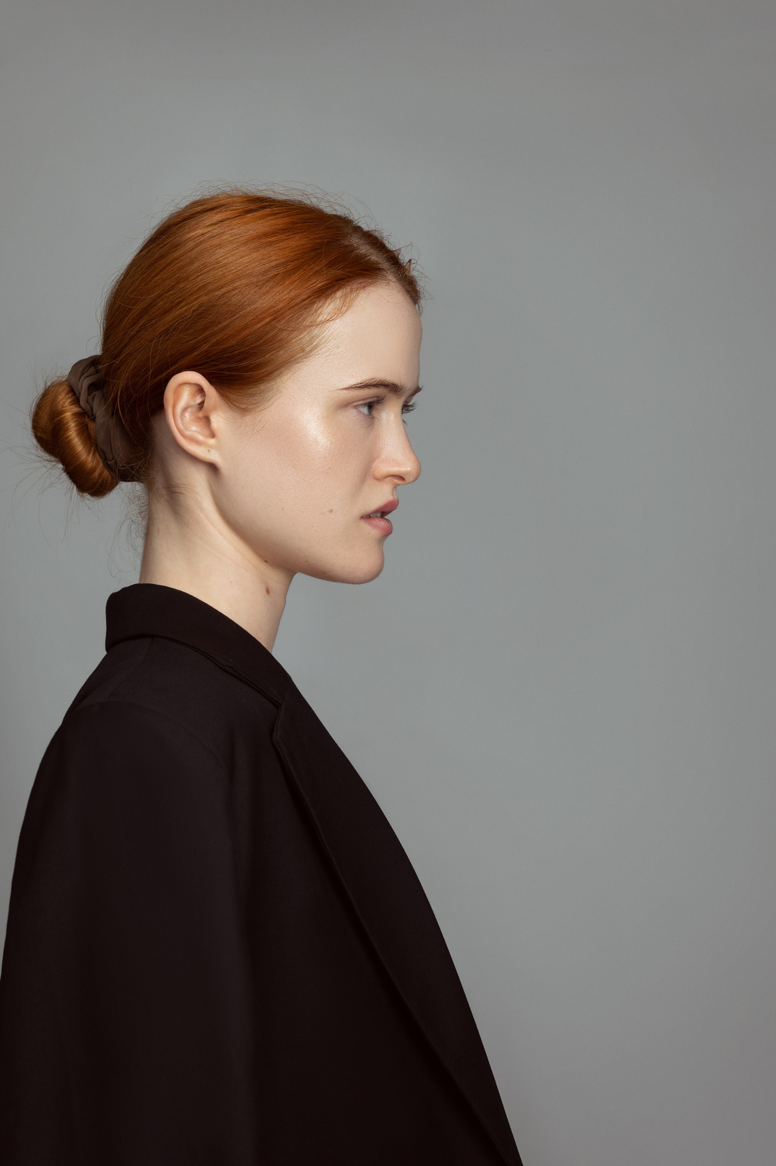 Портрет рыжеволосой девушки-модели в черном пиджаке на сером фоне. Модельные тесты