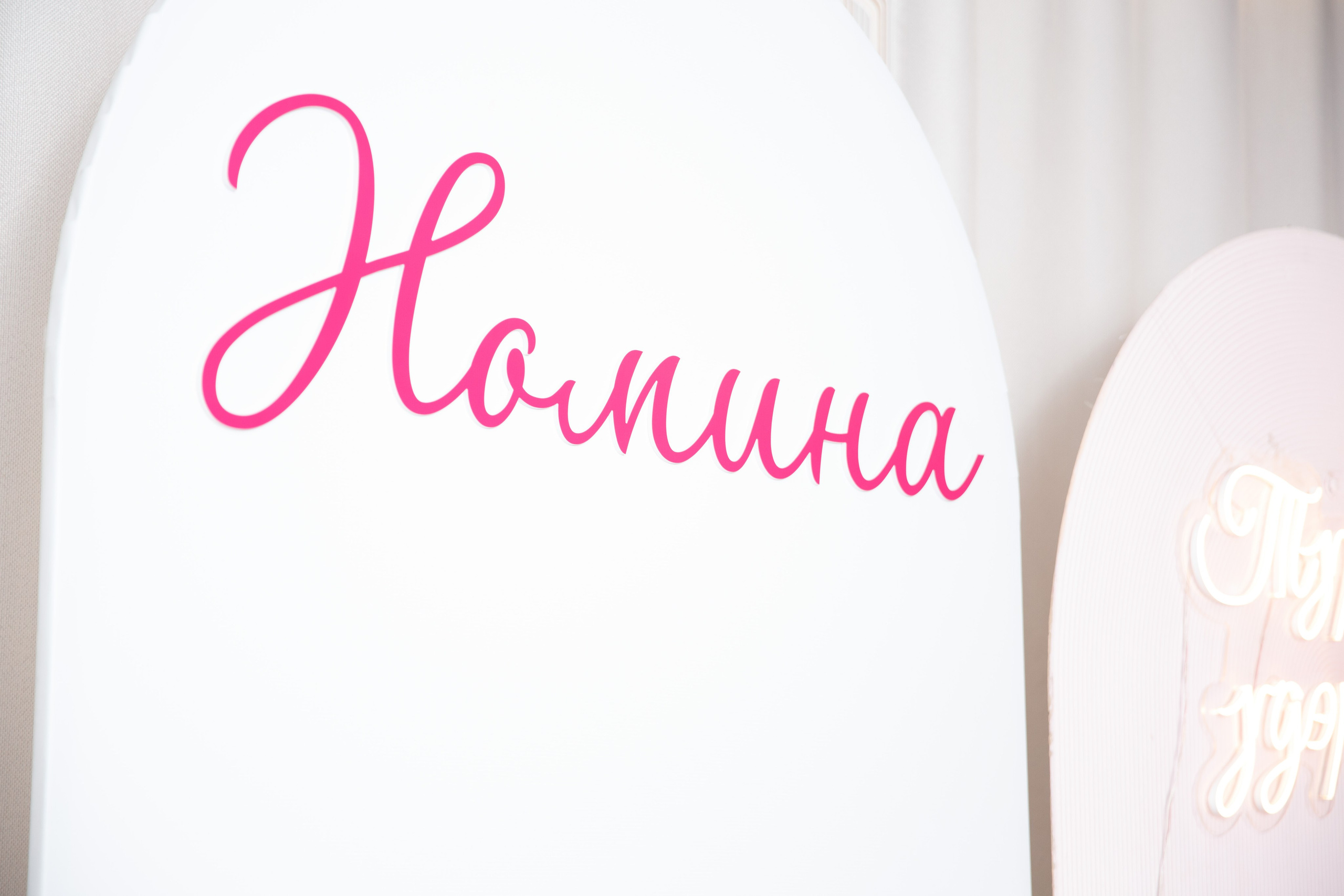  Табличка с именем ребёнка на фоне праздничного оформления.