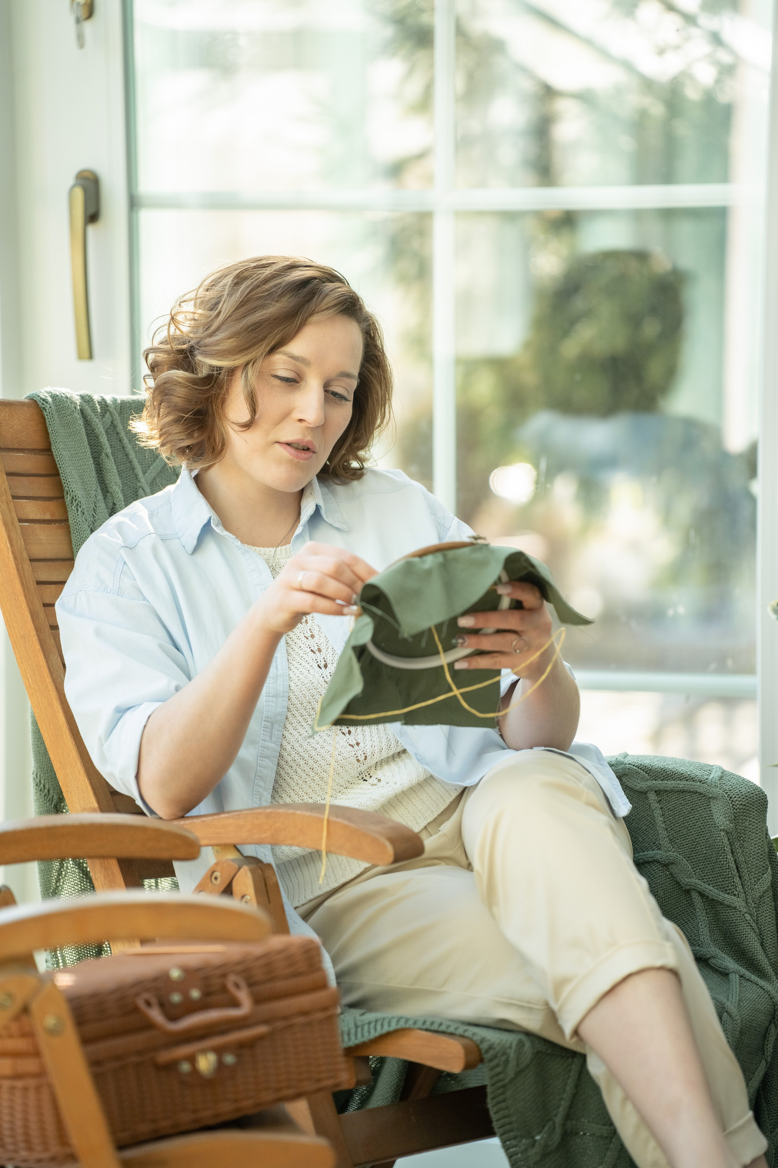 Женщина, девушка вышивает на пяльцах сидя в кресле