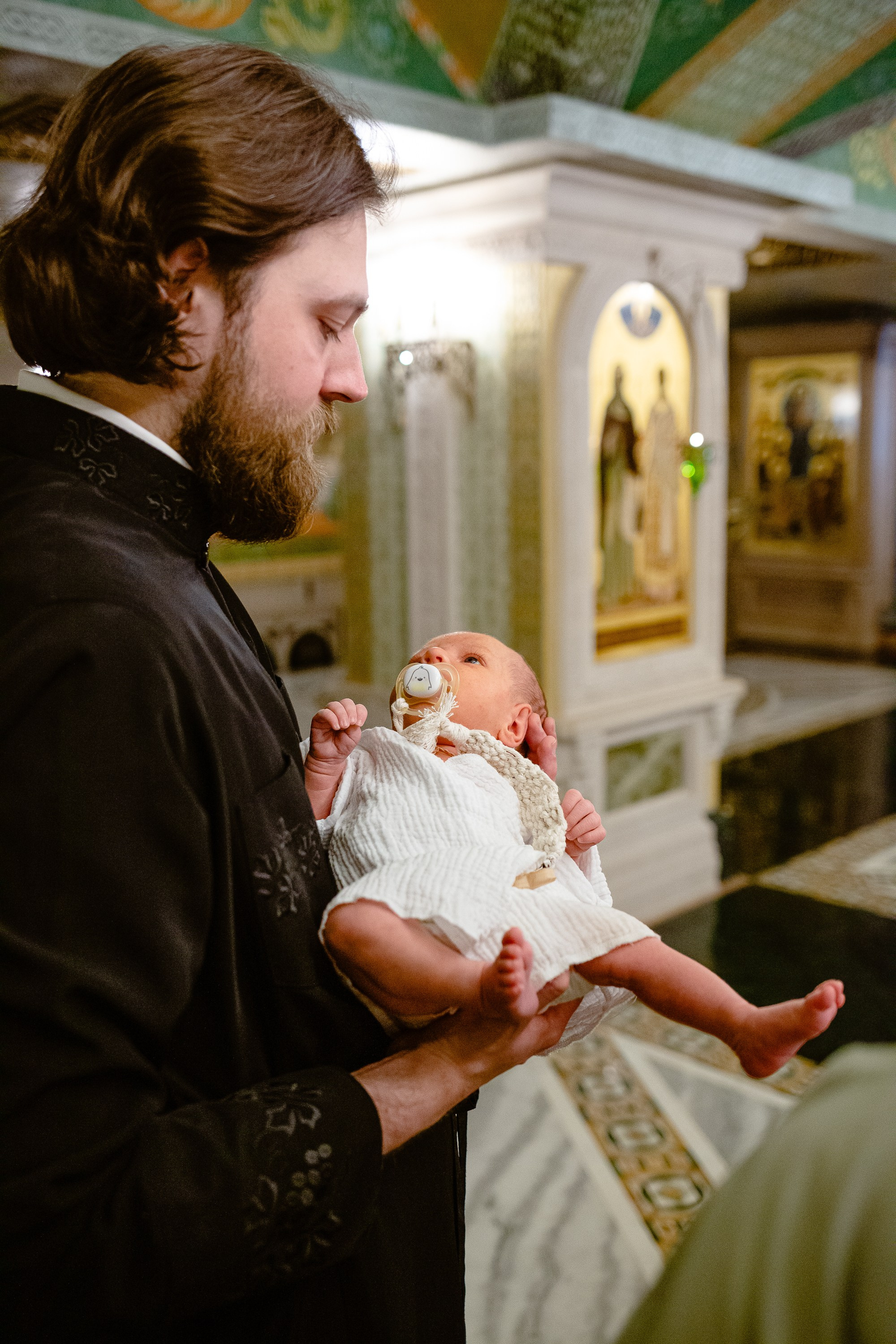 Фотосъемка крещения в сретенском монастыре. Папа держит на руках ребенка, который будет креститься.