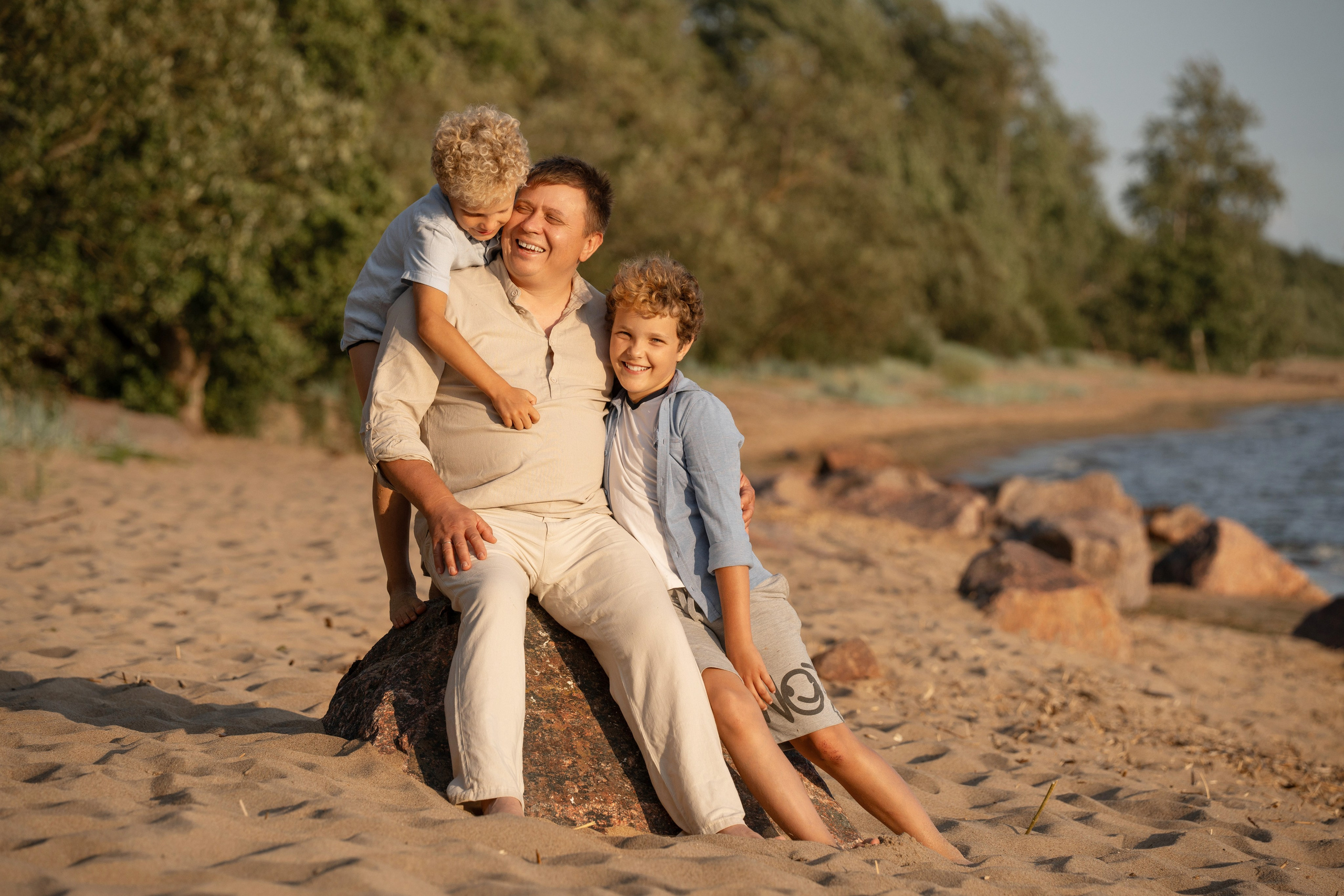 Папа с детьми веселится на берегу залива.