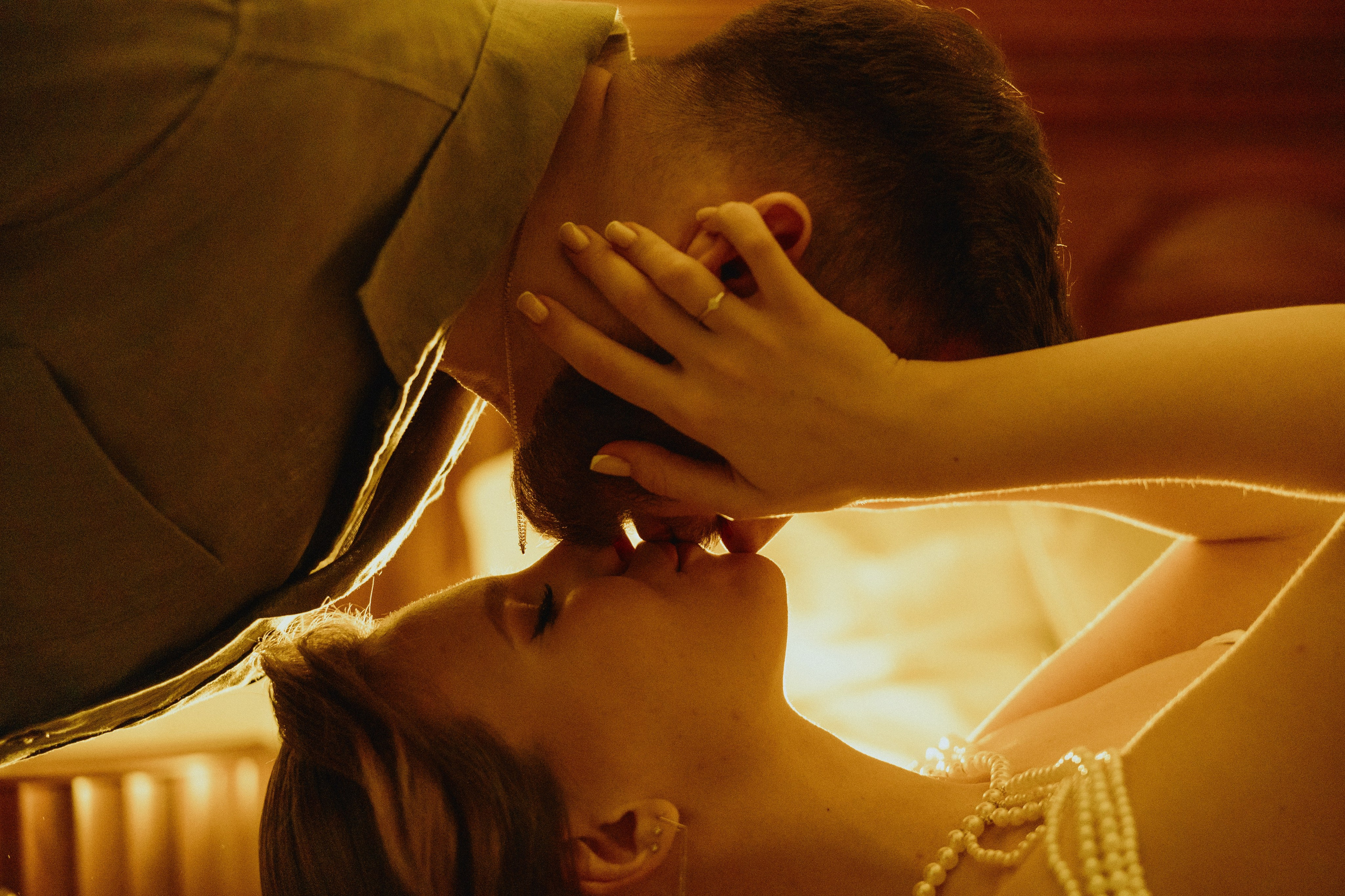 Пара целуется при свечах, освещенная теплым светом.