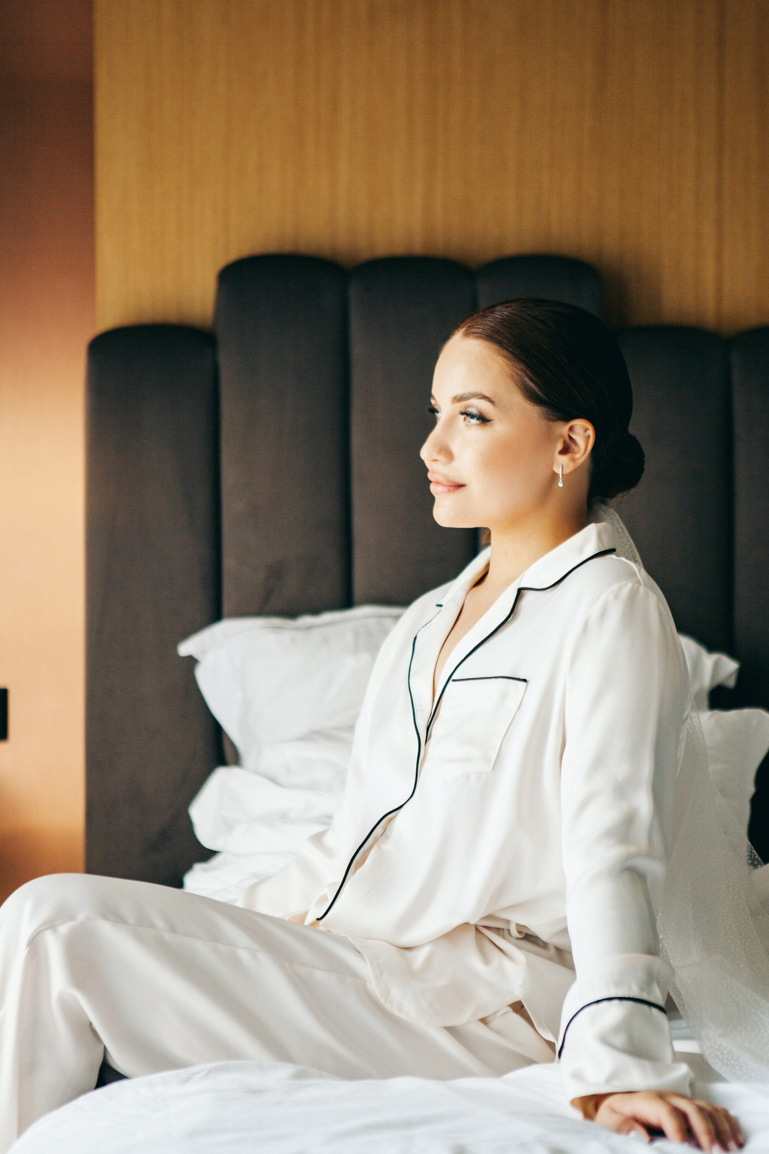 невеста в пижаме сидит на кровати в отеле