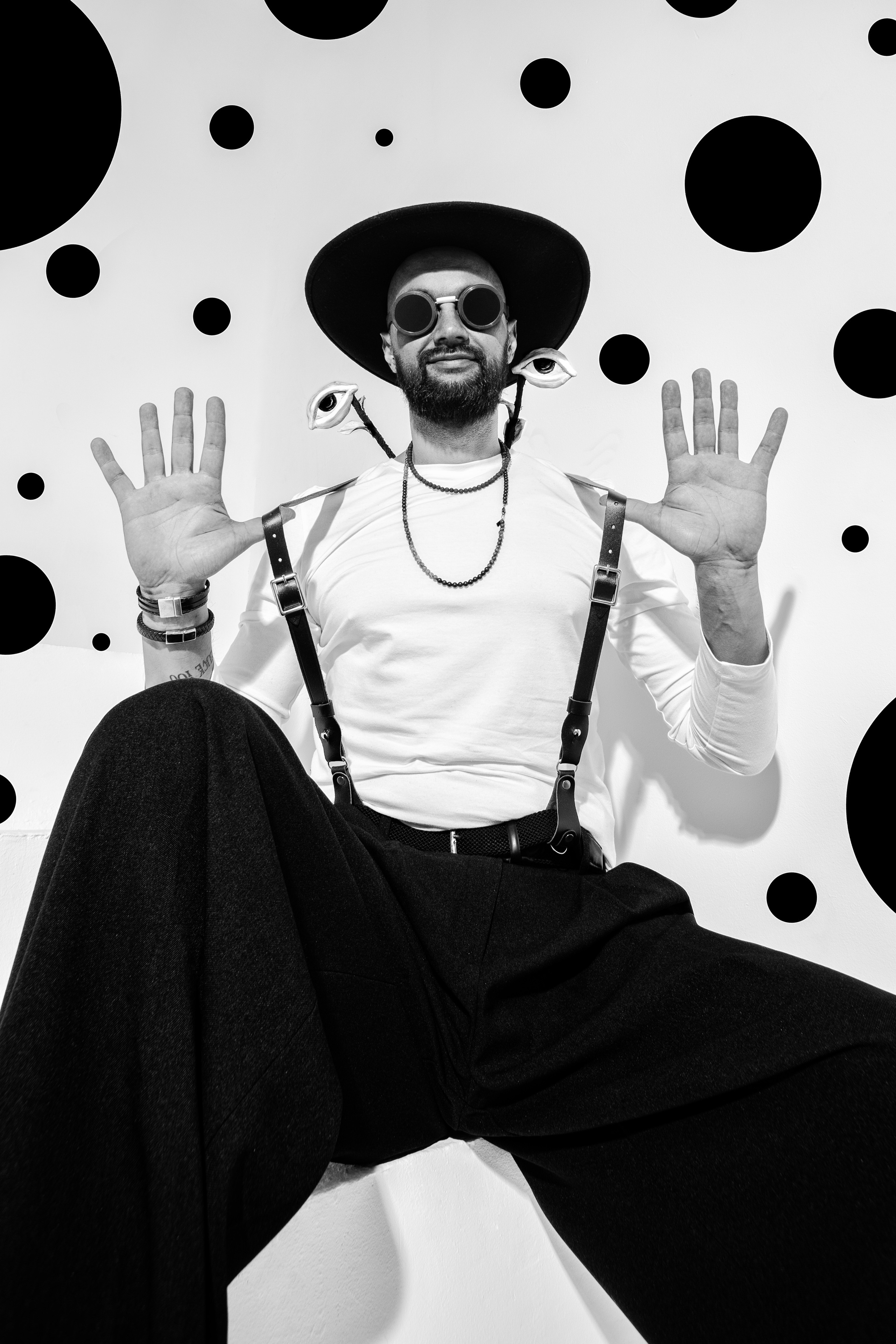 сюрреалистический протерт, креативный портрет черно белый, мужчина в шляпе в брюках на подтяжках на фоне черных кругов
