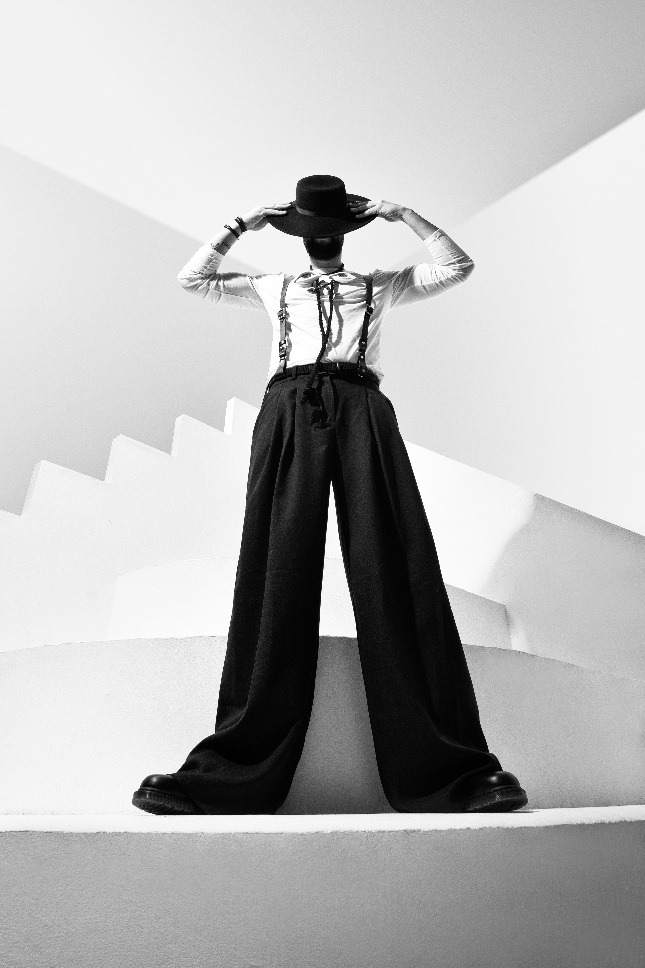 сюрреалистический протерт, креативный портрет черно белый, мужчина в шляпе в брюках на подтяжках в геометрическом пространстве 