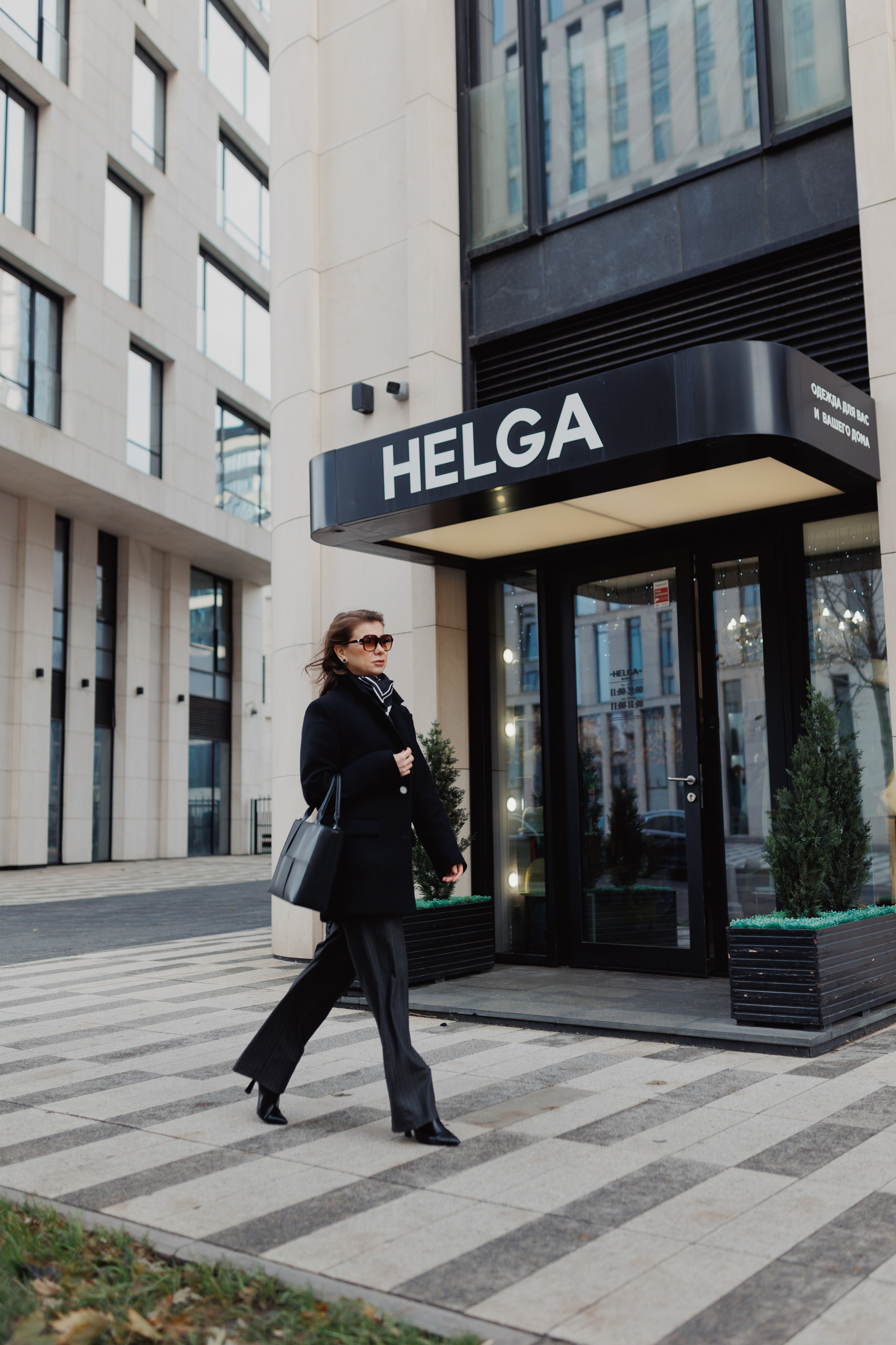 Ростовой лайфстайл-кадр: женщина-адвокат идёт по улице в бизнес-квартале на фоне дорогой архитектуры. Съёмка на локации.