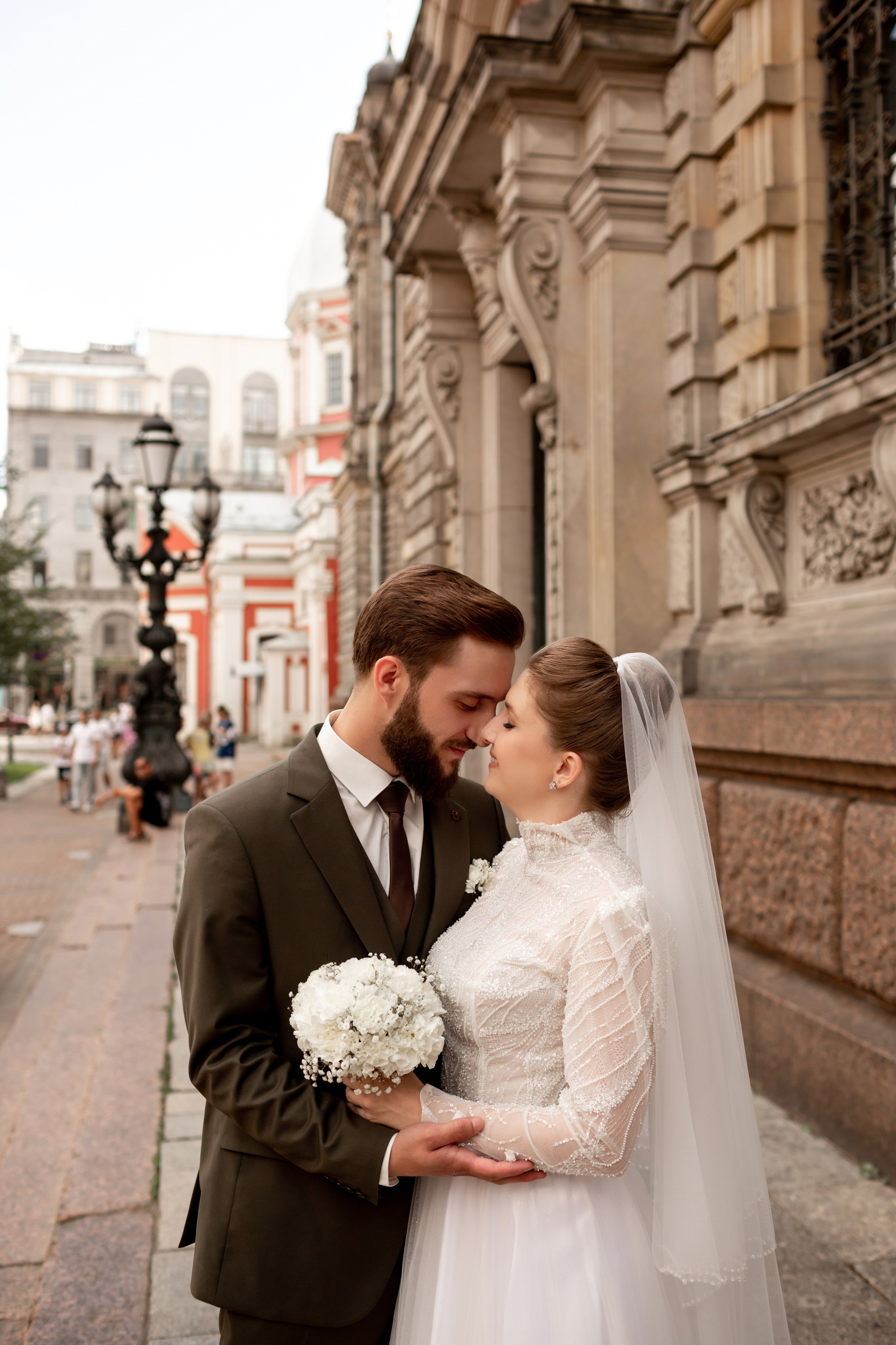 Жених в оливковом костюме целует невесту