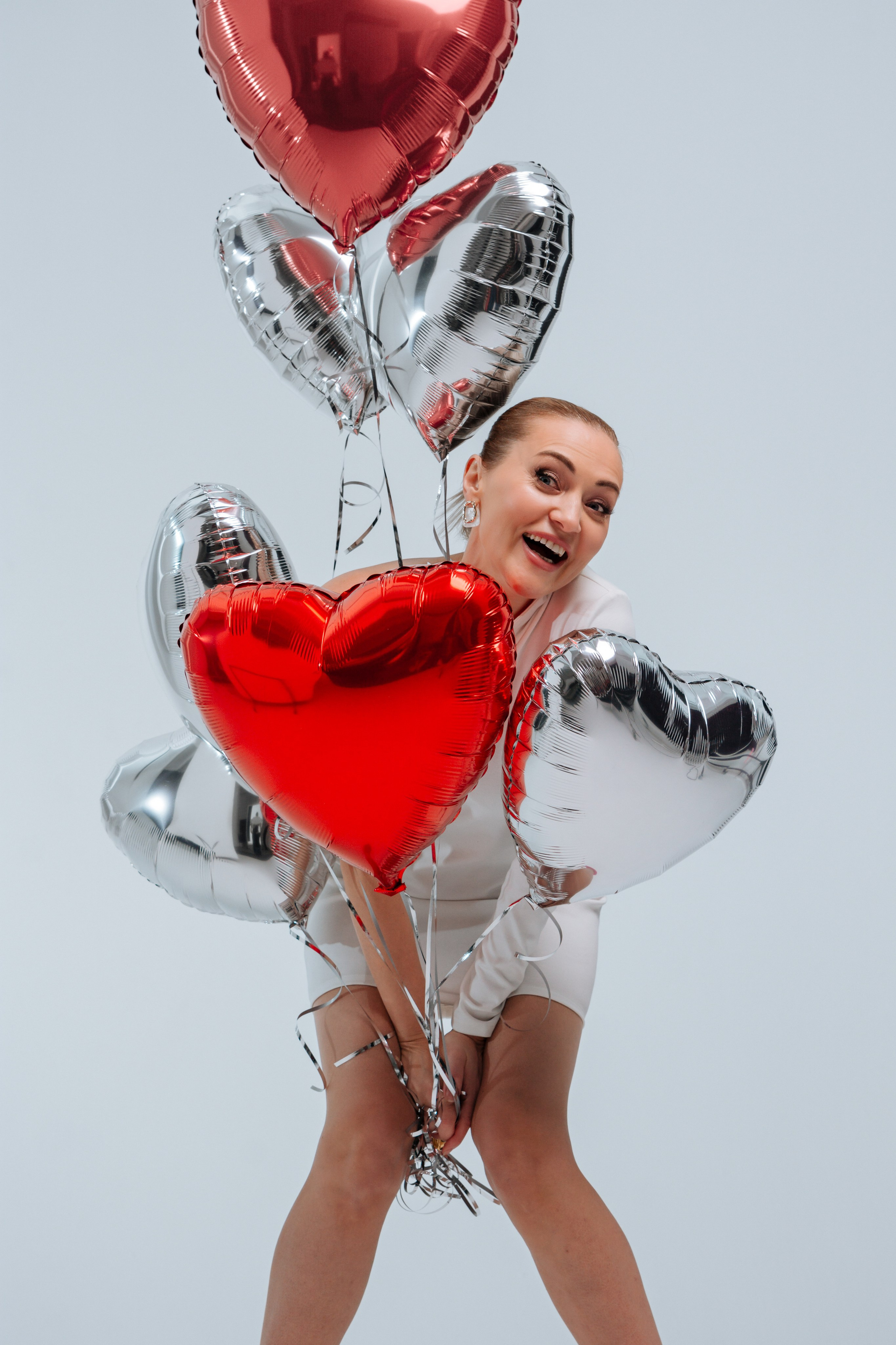 Хрупкая красавица в белом платьице. Игривые разноцветные сердца-шарики в руках. Озорное олицетворение пробуждающейся весенней любви.