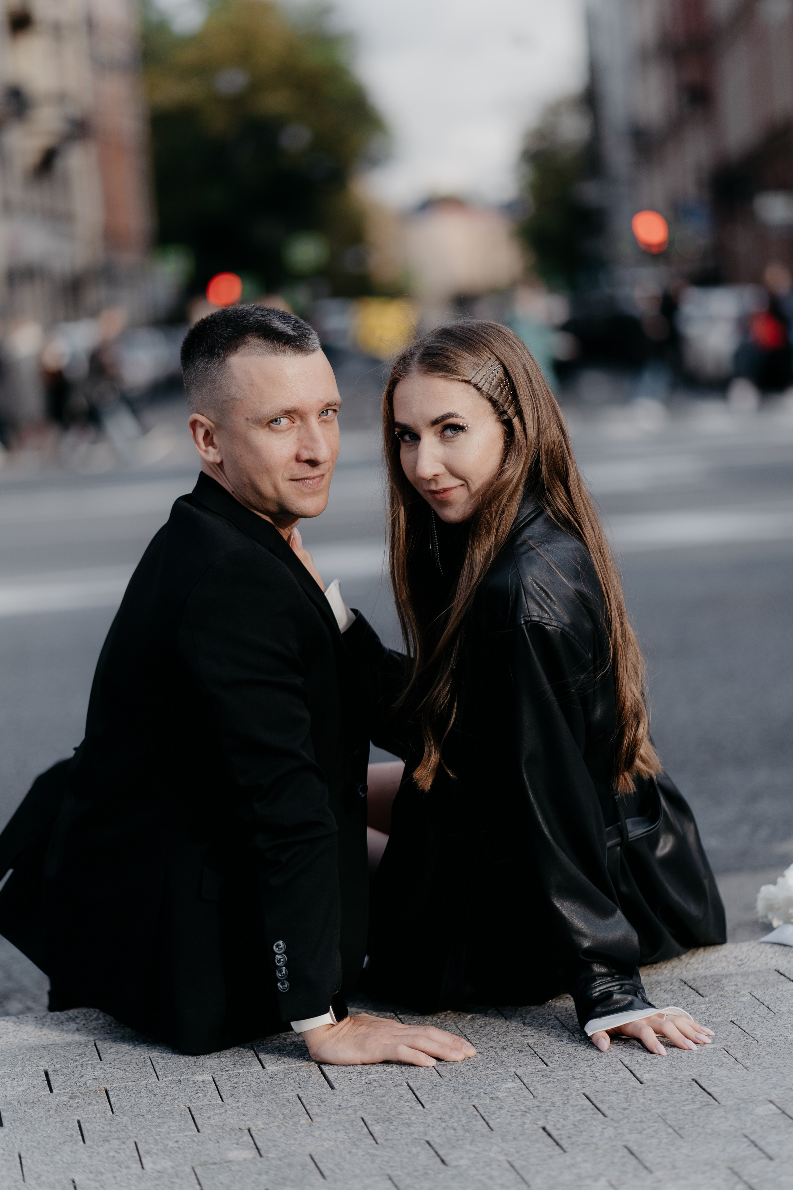 Пара в кожаных куртках сидят на асфальте