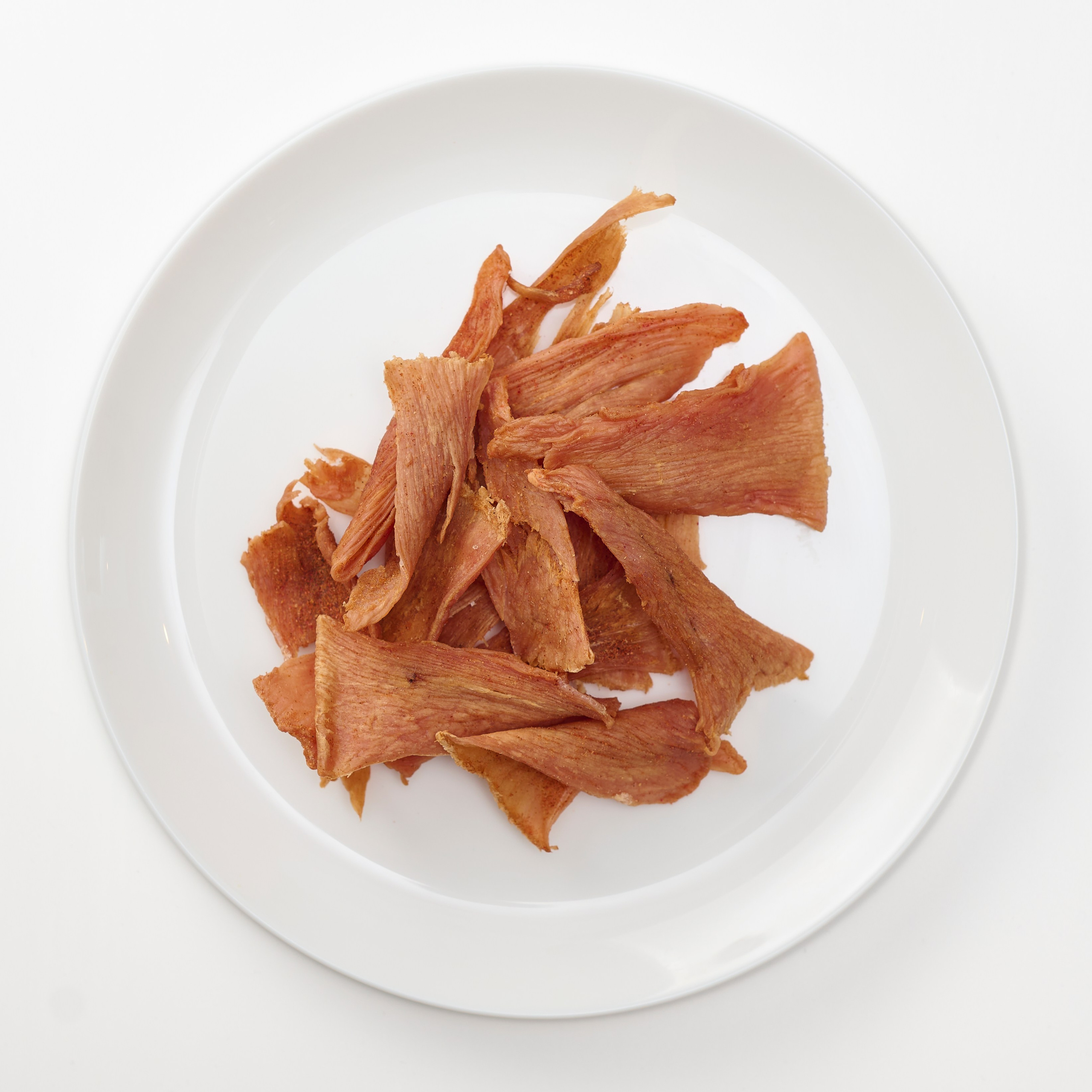 фотосъемка мясных чипсов на тарелке на белой скатерти 