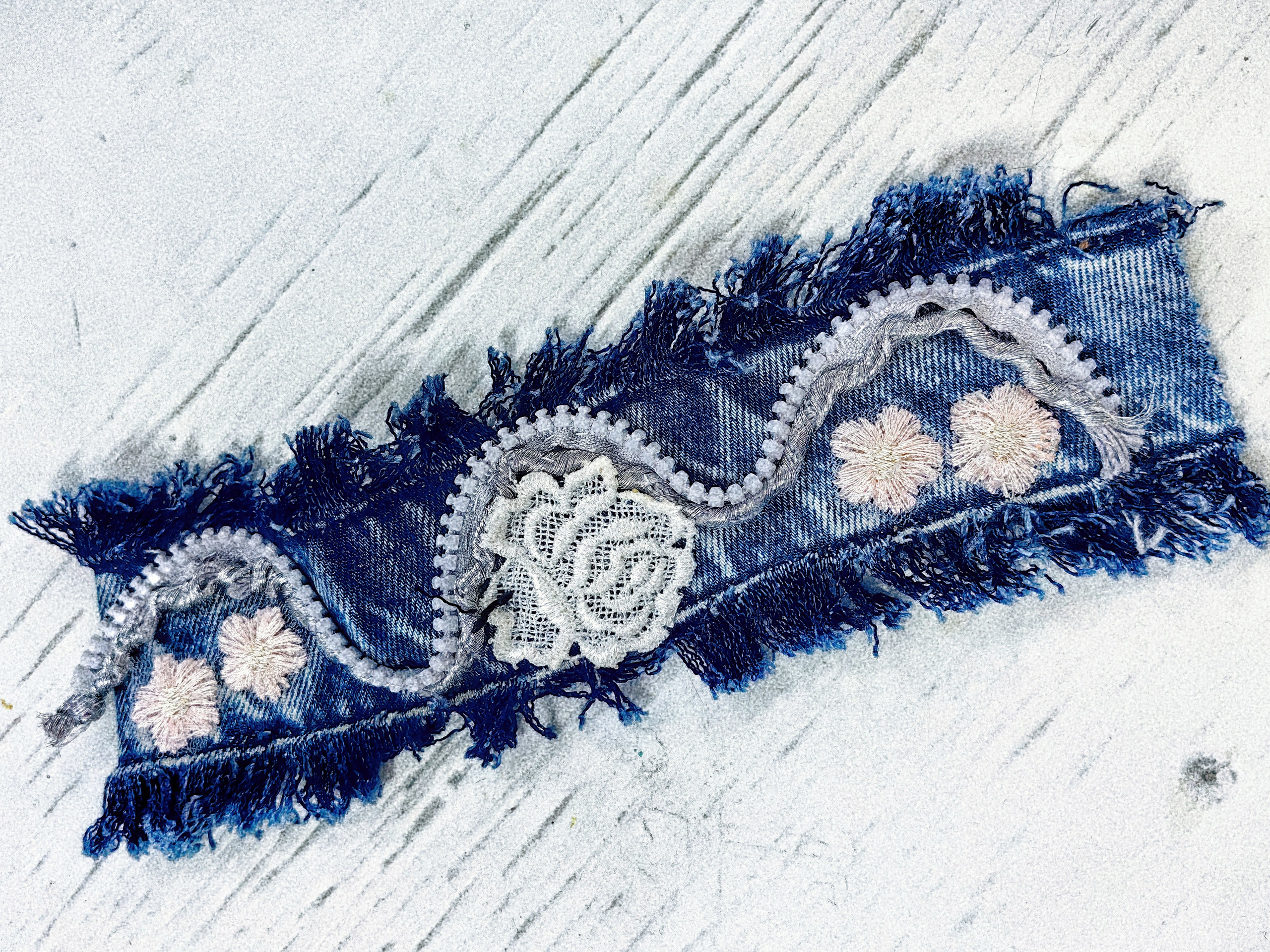 Красивый браслет из джинсы дополнен изящной фурнитурой в виде кружева и серебряной цепочки.