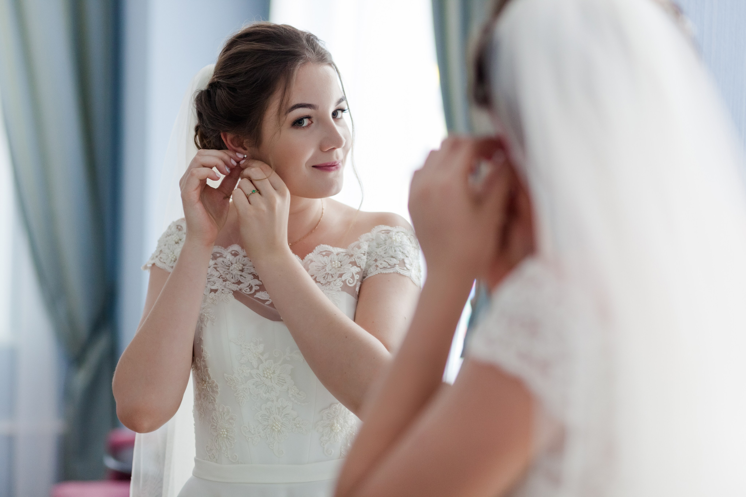 Невеста готовиться к свадьбе одевает серьги
