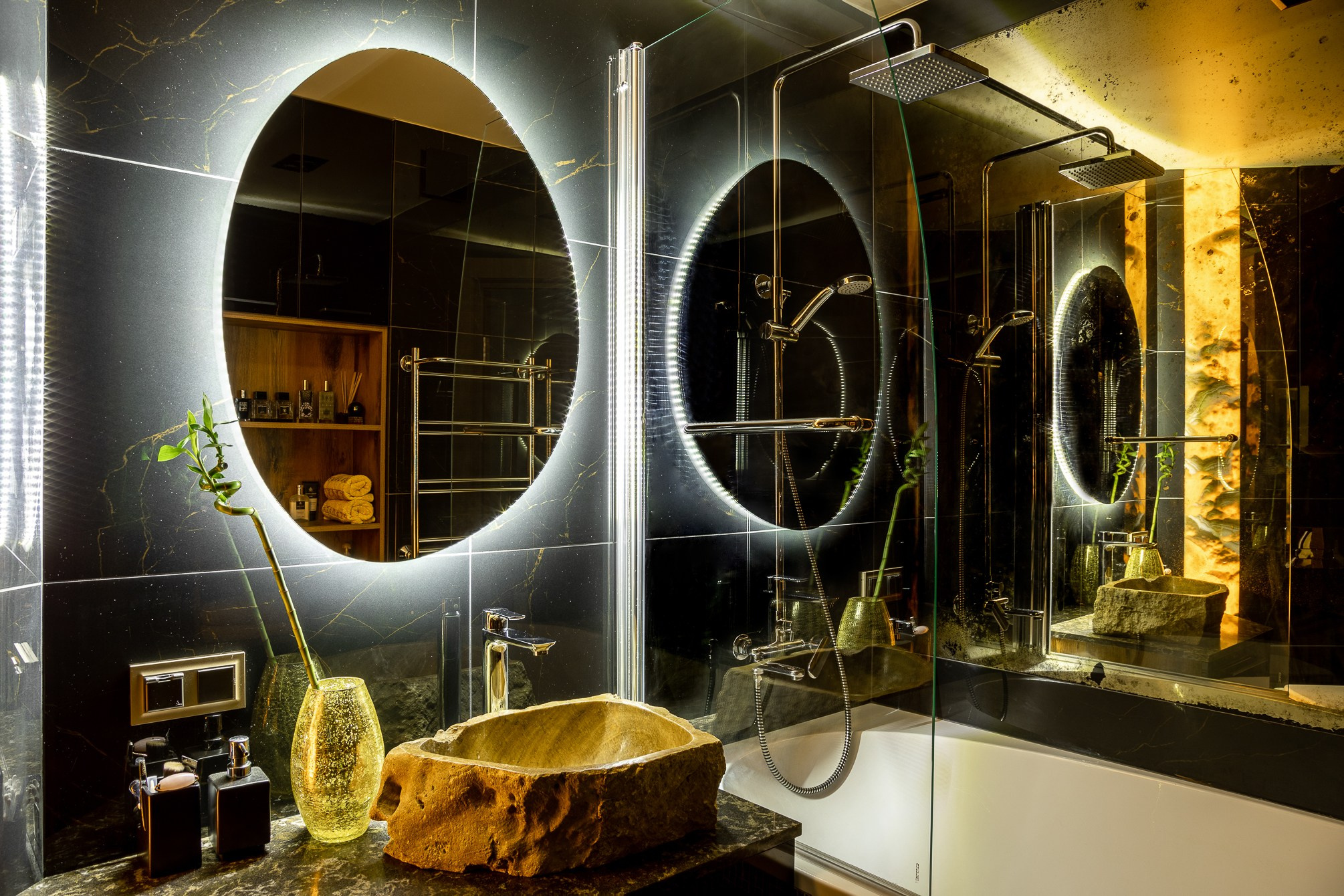 Овальное зеркало в ванной с оранжевой подсветкой в душевой.