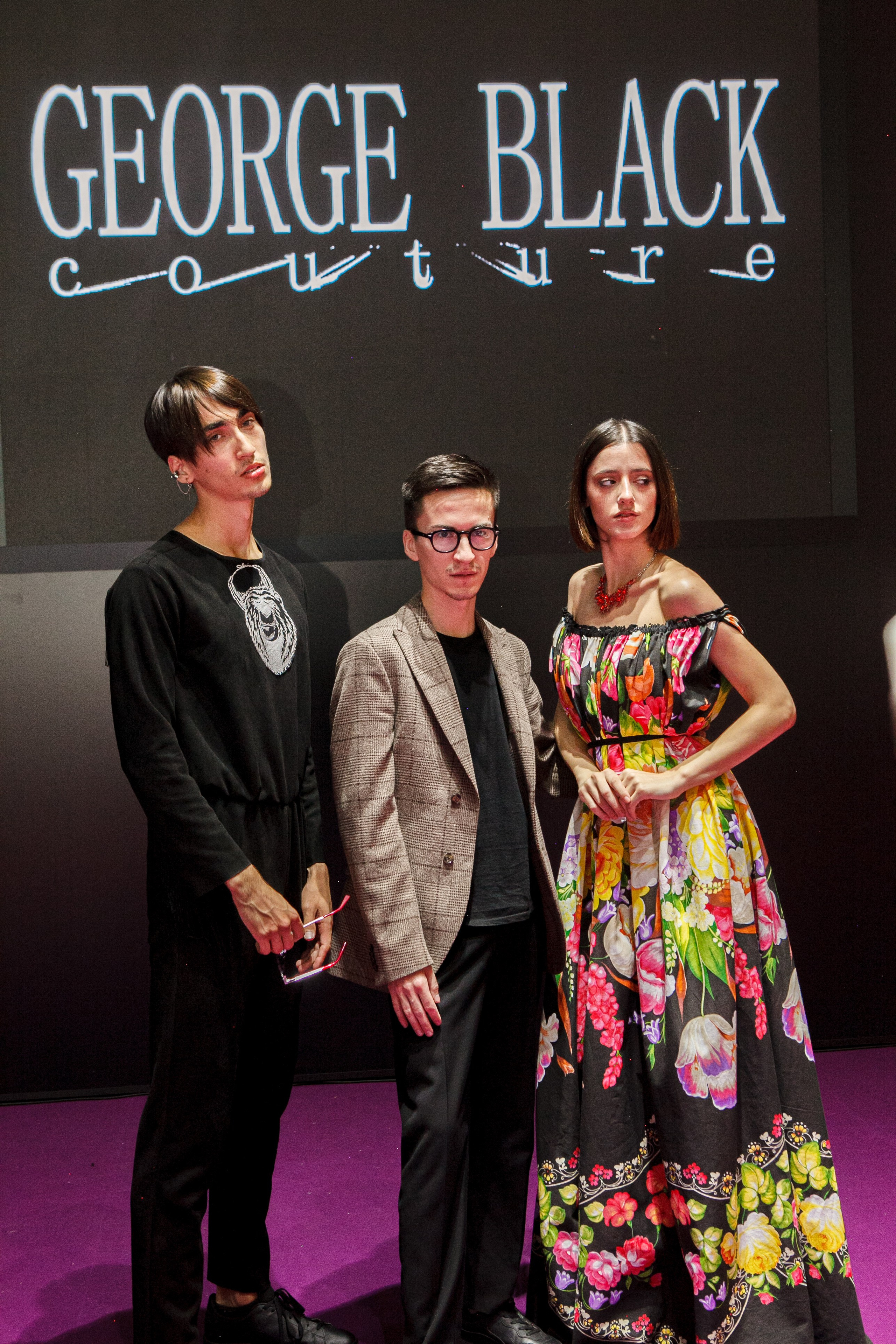  "Модели в ярких нарядах проходят по подиуму во время показа мод, освещенные яркими софитами и окруженные восторженными зрителями."