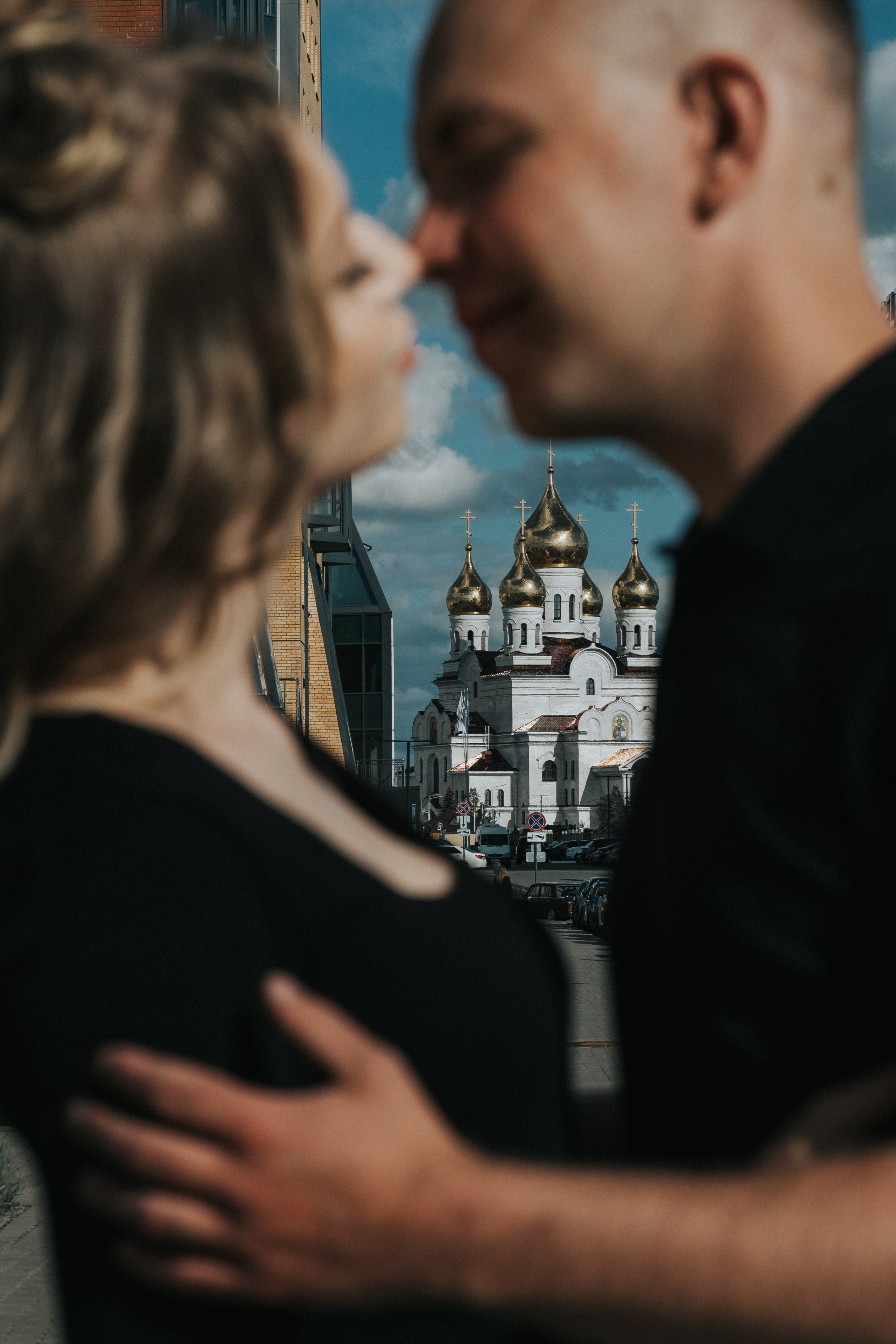 Молодая пара мужчина и девушка целуются  в городских локациях в черных футболках и синих джинсах не в резкости а в резкости Михайло-архангельский собор , лав стори для влюбленной пары на кануне свадьбы