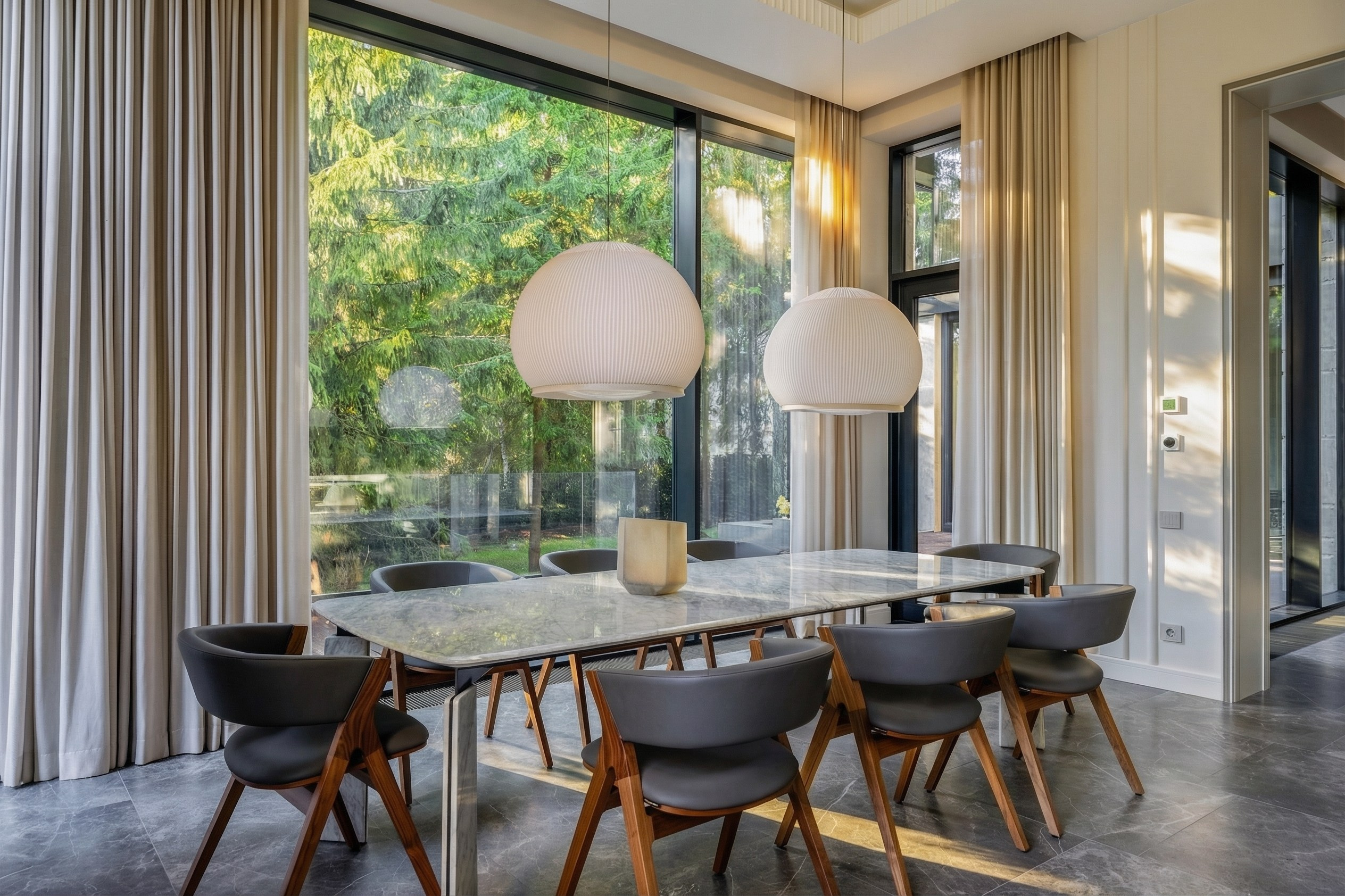 Обеденная зона в премиальном доме 1240 м²: мраморный стол, дизайнерские стулья и плиссированные светильники-шары на фоне панорамных окон с видом на лес, проект Валерии Котович.